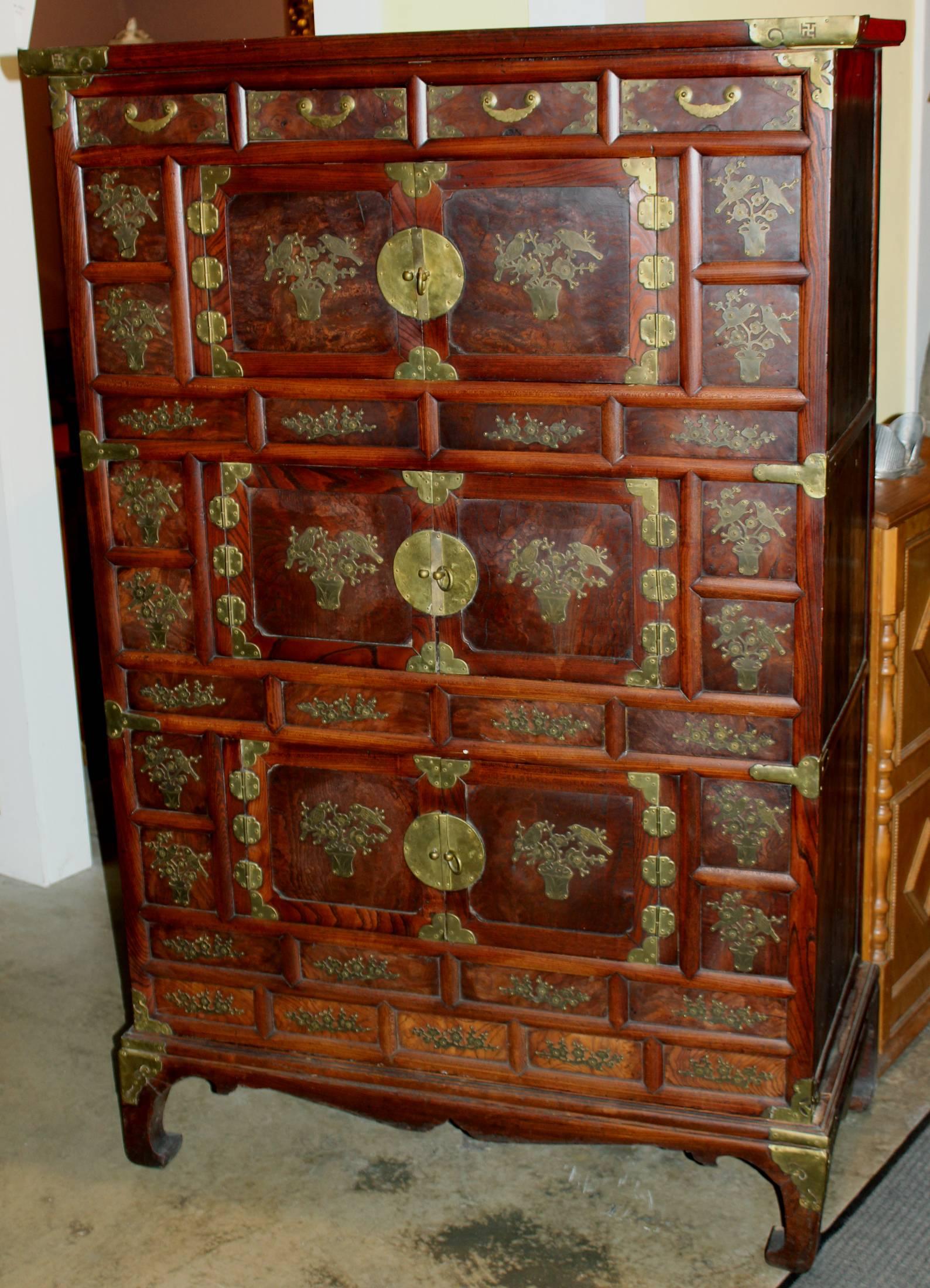 A beautiful example of a late 19th century Korean elmwood cabinet with brass mounts, four small fitted drawers over three sets of fitted banded burl paneled double doors which open to reveal paper lined storage compartments. Each of the double doors