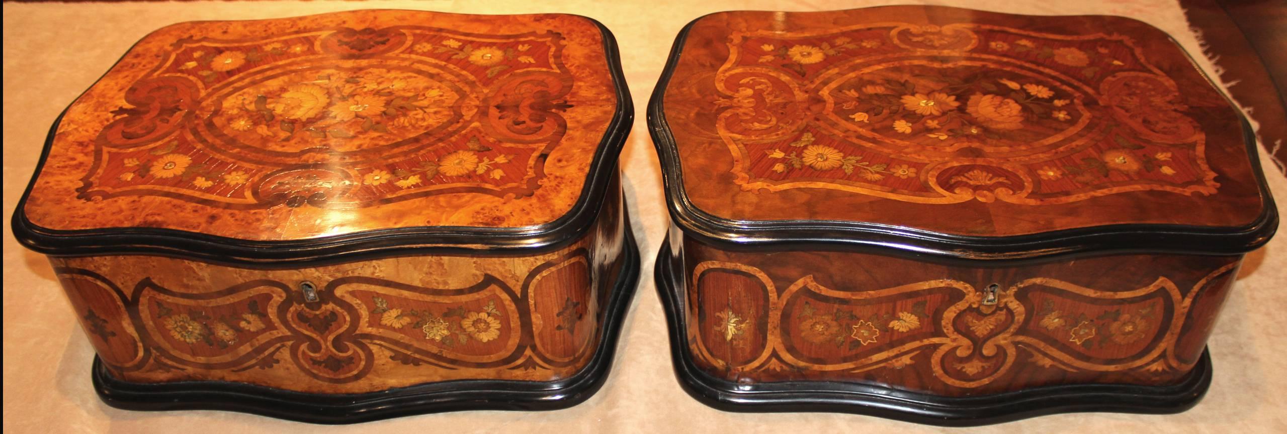 A spectacular pair of serpentine marquetry boxes with burl and satinwood foliate inlay with tufted silk interior upholstery and ebonized trim and base, 19th century, French.