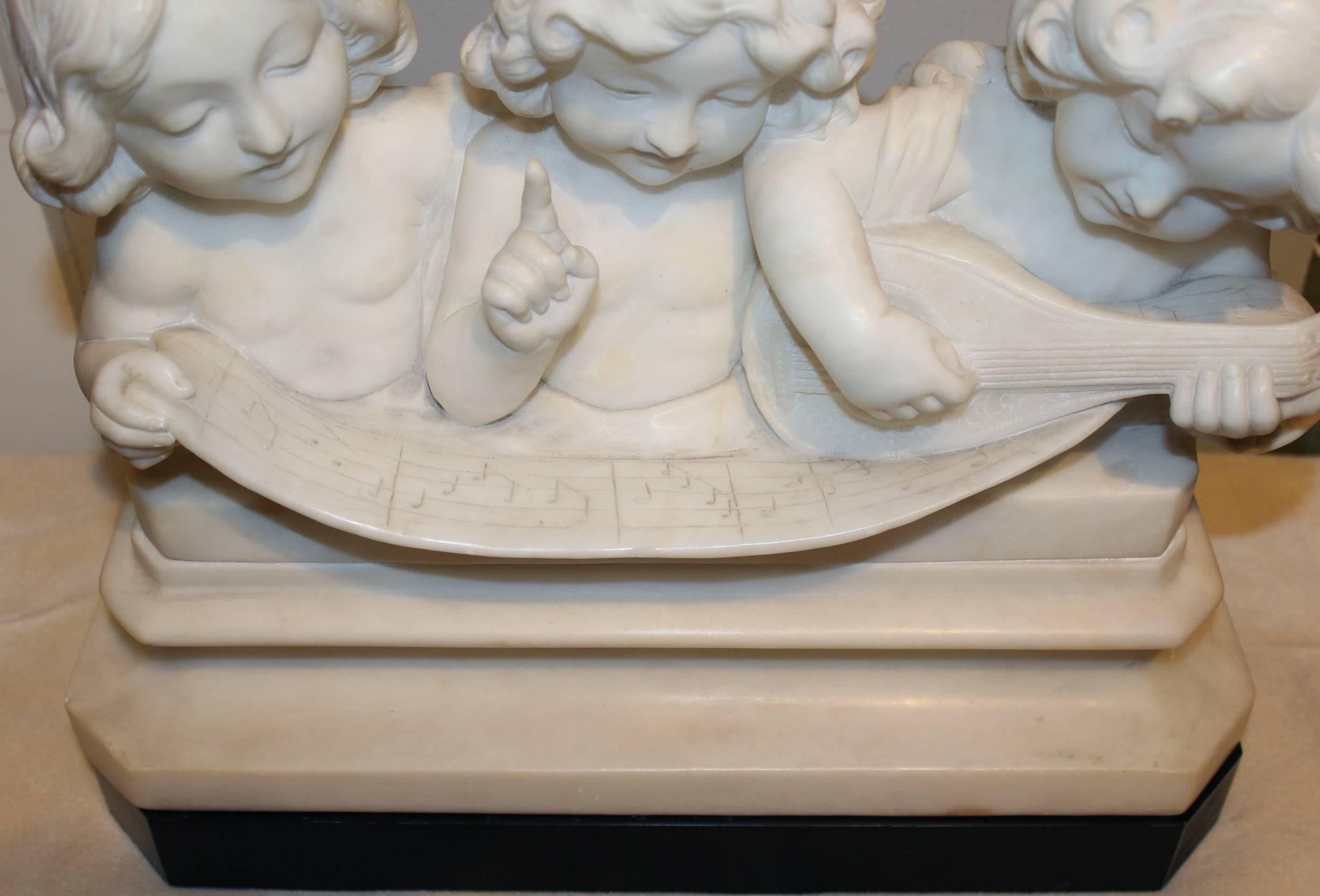 A fine example of a carved alabaster or marble figural sculpture of three children singing with a musical scroll signed on verso by Italian sculptor Adolfo Cipriani (active 1880-1930). The figure on the right is playing the mandolin. Raised on a