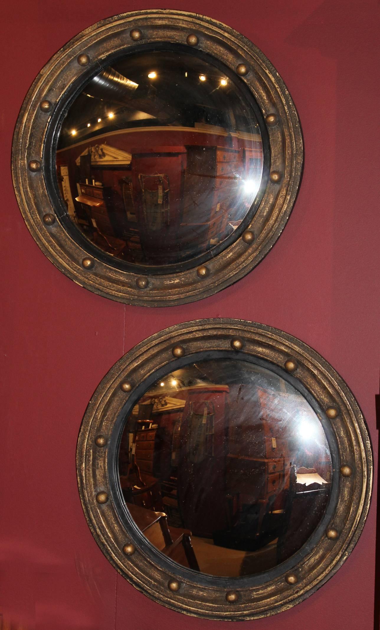 Splendid pair of custom convex girandole mirrors, each with a full set of spherules, ebonized inset and giltwood molded frames. This pair dates to the 20th century.
 