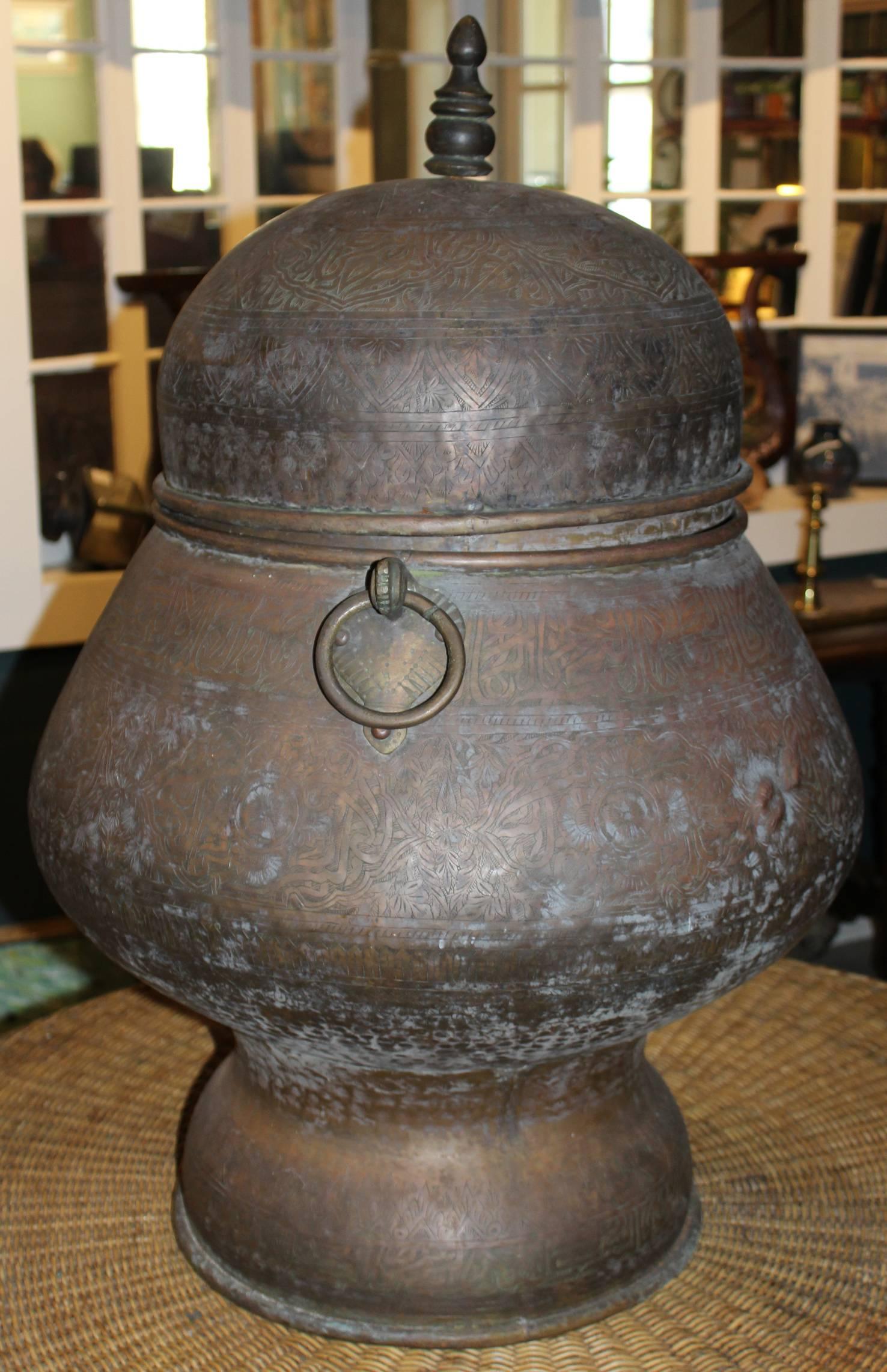 A fine Middle Eastern or Persian covered handled copper palace urn with great form, chased with hand-hammered geometric and foliate designs and decoration, the cover with turned finial and body fitted with two ring form handles. Great overall patina.