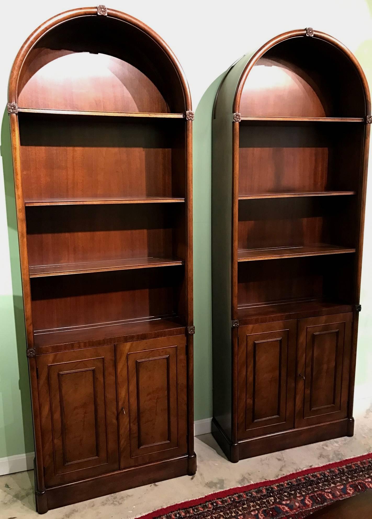 A fine pair of arched mahogany bookcases or china cabinets, from the Kaplan Furniture Beacon Hill Collection, each with one permanent and two adjustable shelves surmounting two doors, which open to reveal one adjustable interior shelf. The shelves