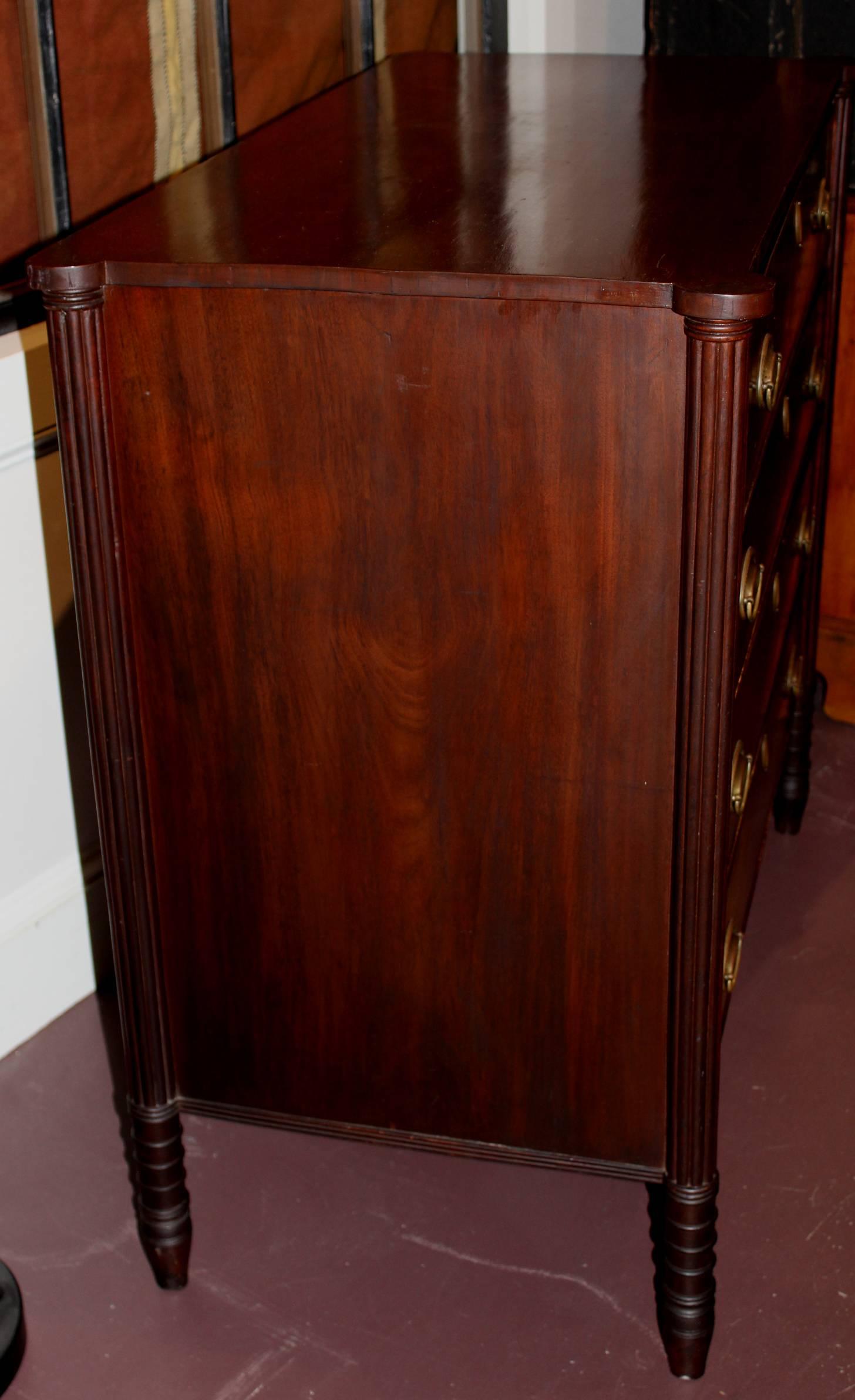 An American Sheraton mahogany four-drawer chest, circa 1820 with four crossbanded and beaded drawers with rectangular top with ovolu corners above receded pilasters over turned and tapered legs. Probably of Massachusetts origin. Nice brass hardware.