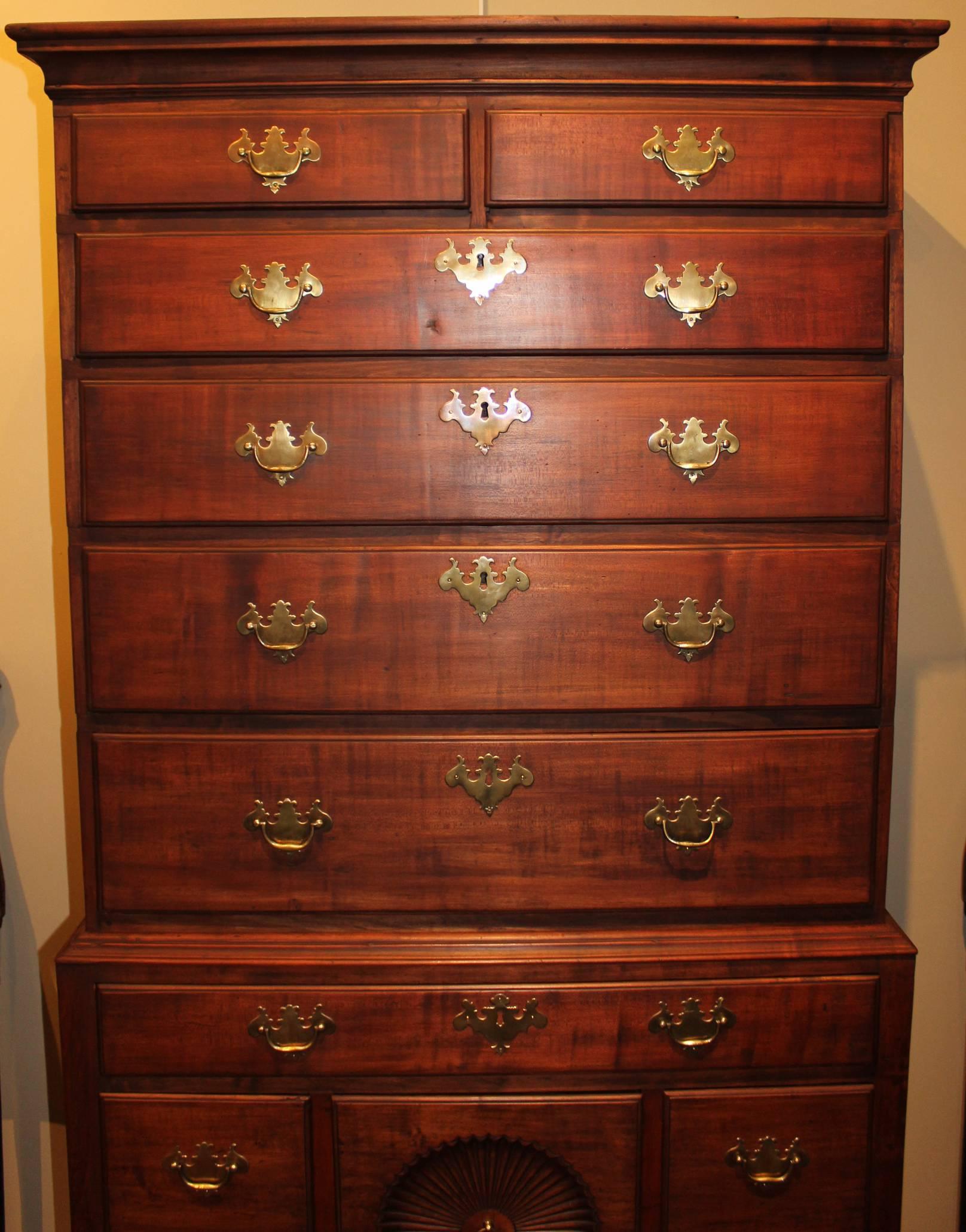This handsome high chest in figured maple has great verticality having tall Queen Anne legs and a rather narrow and tall upper case. It is a nice early example with rosehead nail construction throughout and a beautifully executed fan in the base.