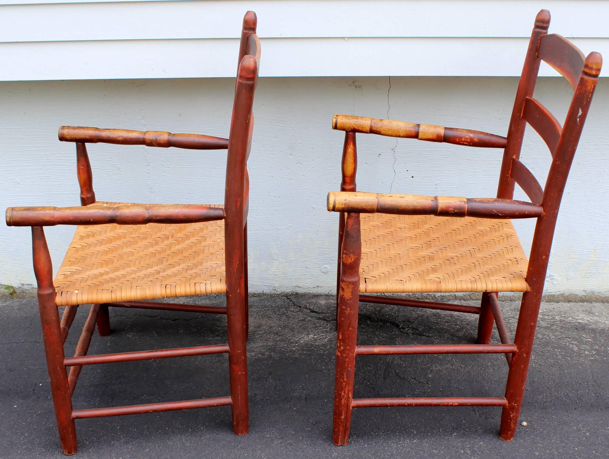 A splendid pair of 19th century country ladder back armchairs in old red finish, with turned arms and front stretchers, and woven split ash seats. Great overall worn red surface finish.