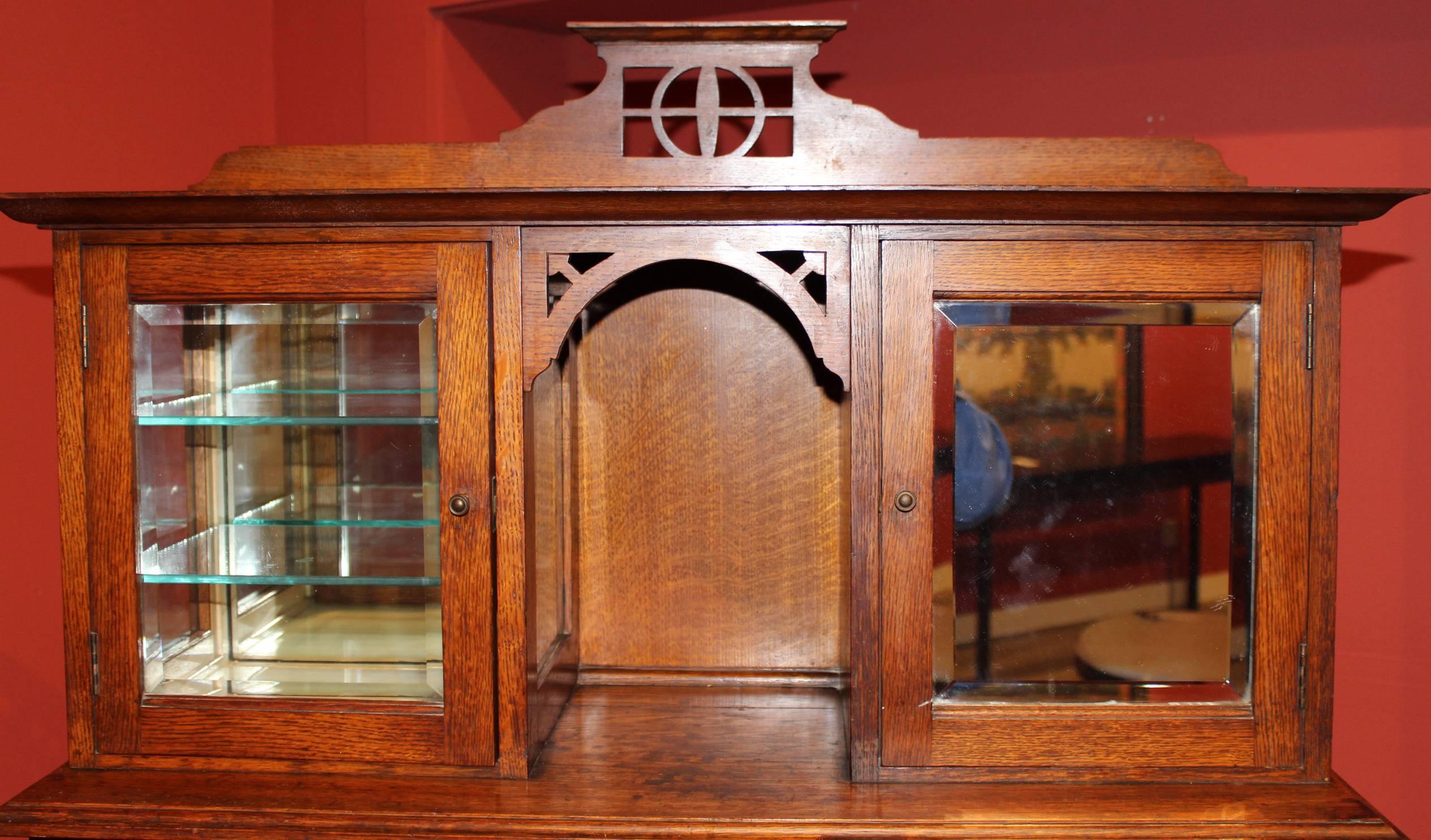 Splendid oak Art Nouveau dental cabinet with polychrome inlay and decorative foliate hardware on the front door panels, upper mirrored compartments with glass shelves on the left and graduated interior shelves on the right, over a center section