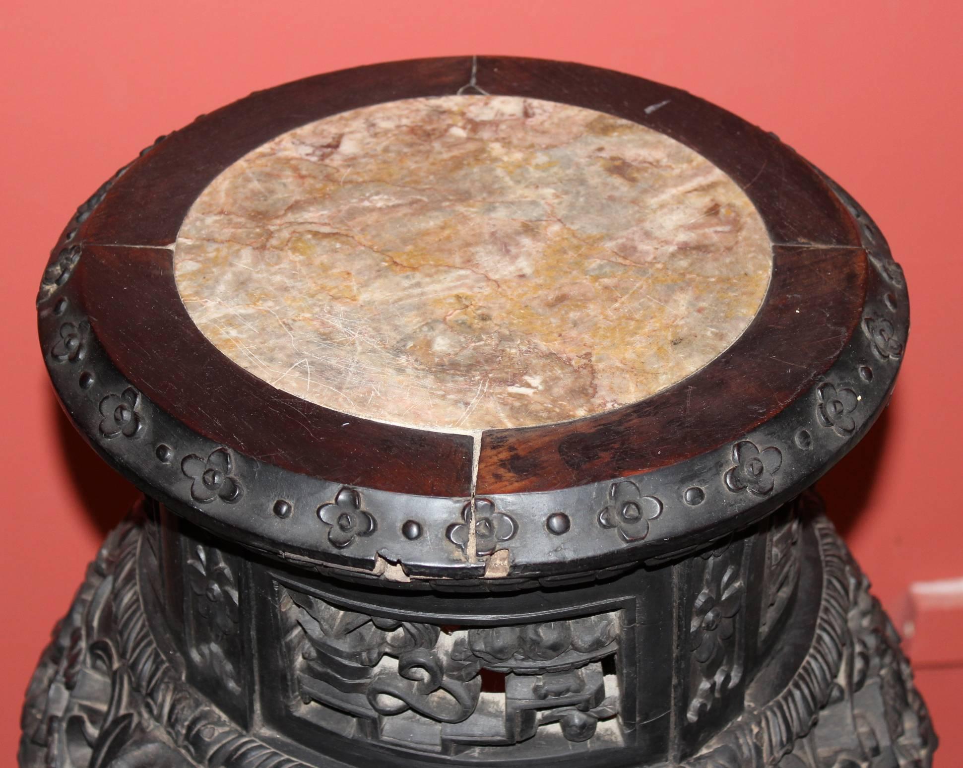 A great form Chinese pierce carved and ebonized hardwood round plant stand with inset marble top and cabriole legs and paw feet, decorated with floral and bird carvings. Dates to the late 19th or early 20th century.