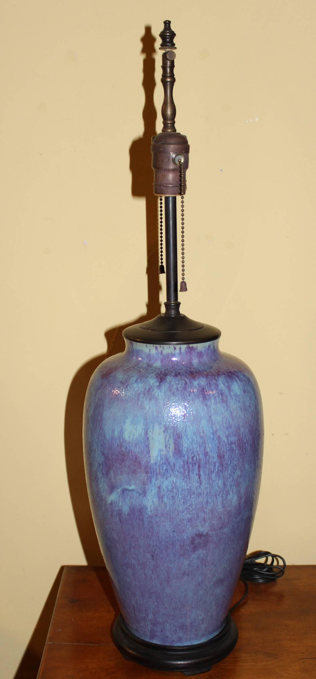 A Chinese flambe glazed porcelain vase in an elongated ovoid form, converted to a two light lamp in the 20th century, on an ebonized wooden base. The vase probably dates to the late 19th century. Good working condition.