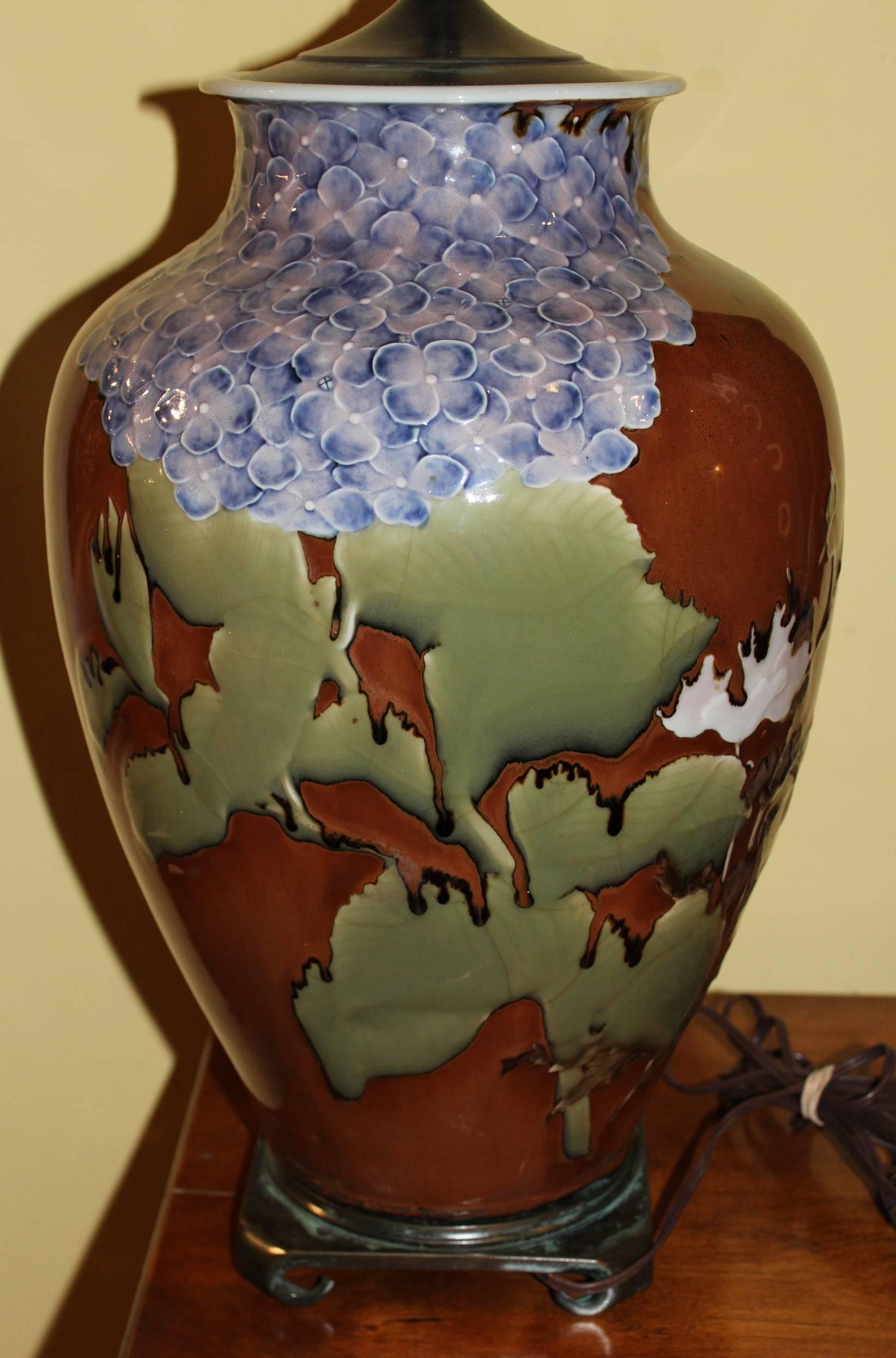 A Japanese studio porcelain vase with polychrome foliate decoration on a brown glaze, converted to a two-light lamp on a decorative metal base. The vase probably dates to the early to mid-20th century. Good working condition.