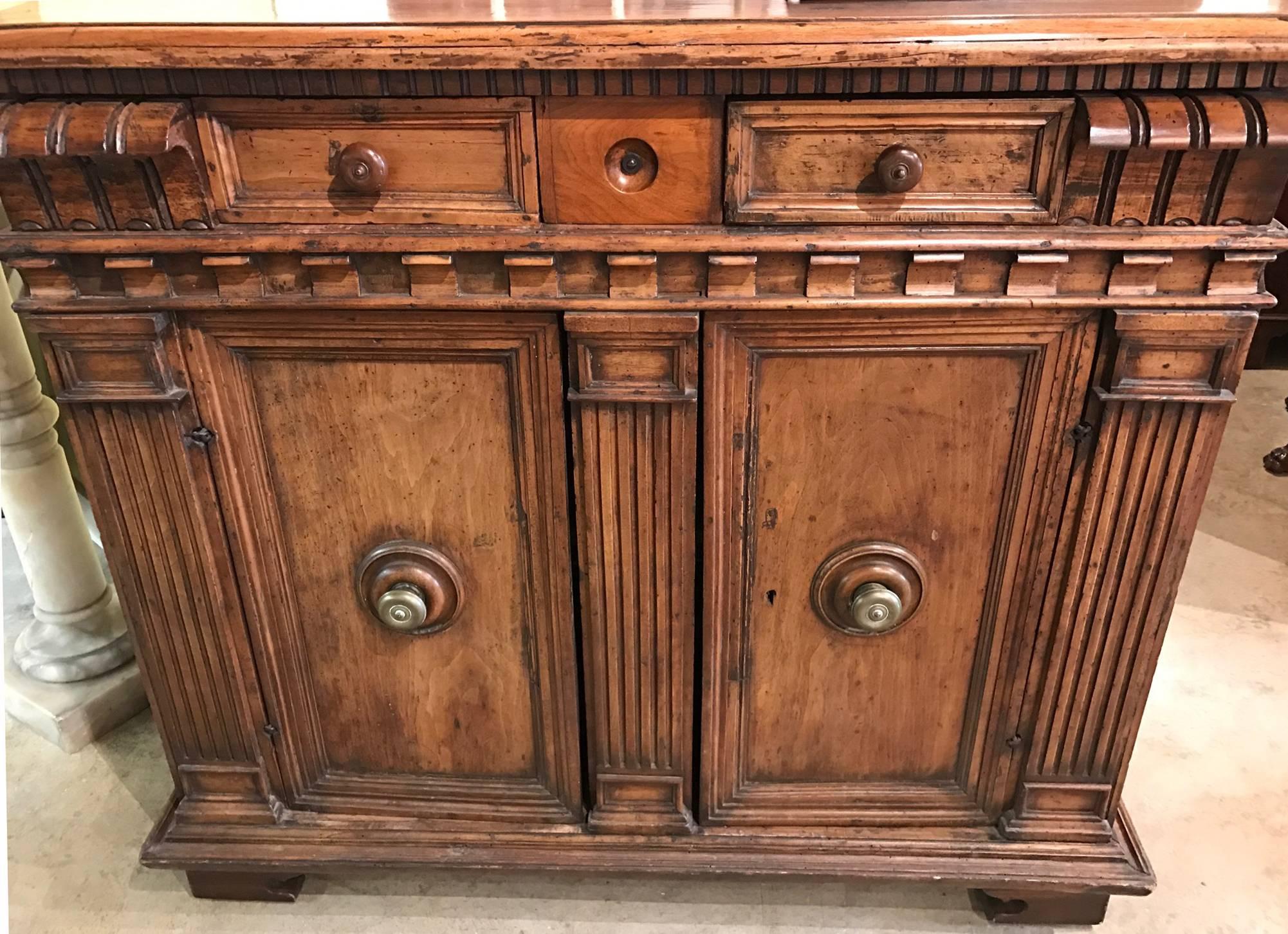 Pregevole credenza in noce italiana del XVIII secolo di grande forma, con piano rettangolare con bordo modanato su tre cassetti piccoli e montati, sormontati da due porte a pannelli che si aprono per rivelare un unico ripiano interno, il tutto