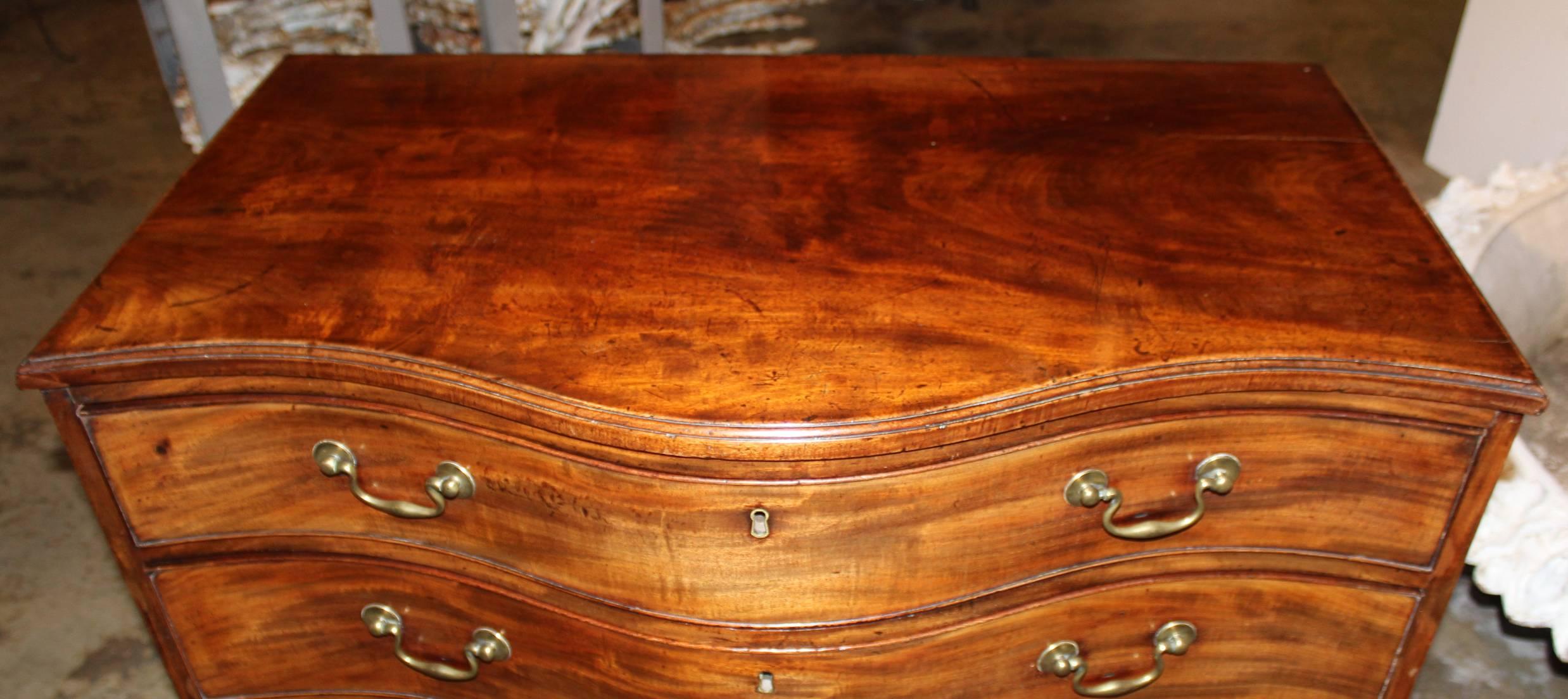 A splendid Georgian mahogany four drawer serpentine chest with dramatic proportions, conforming molded edge top and graduating beaded drawers, all raised by shaped bracket feet. The brasses are possibly original.