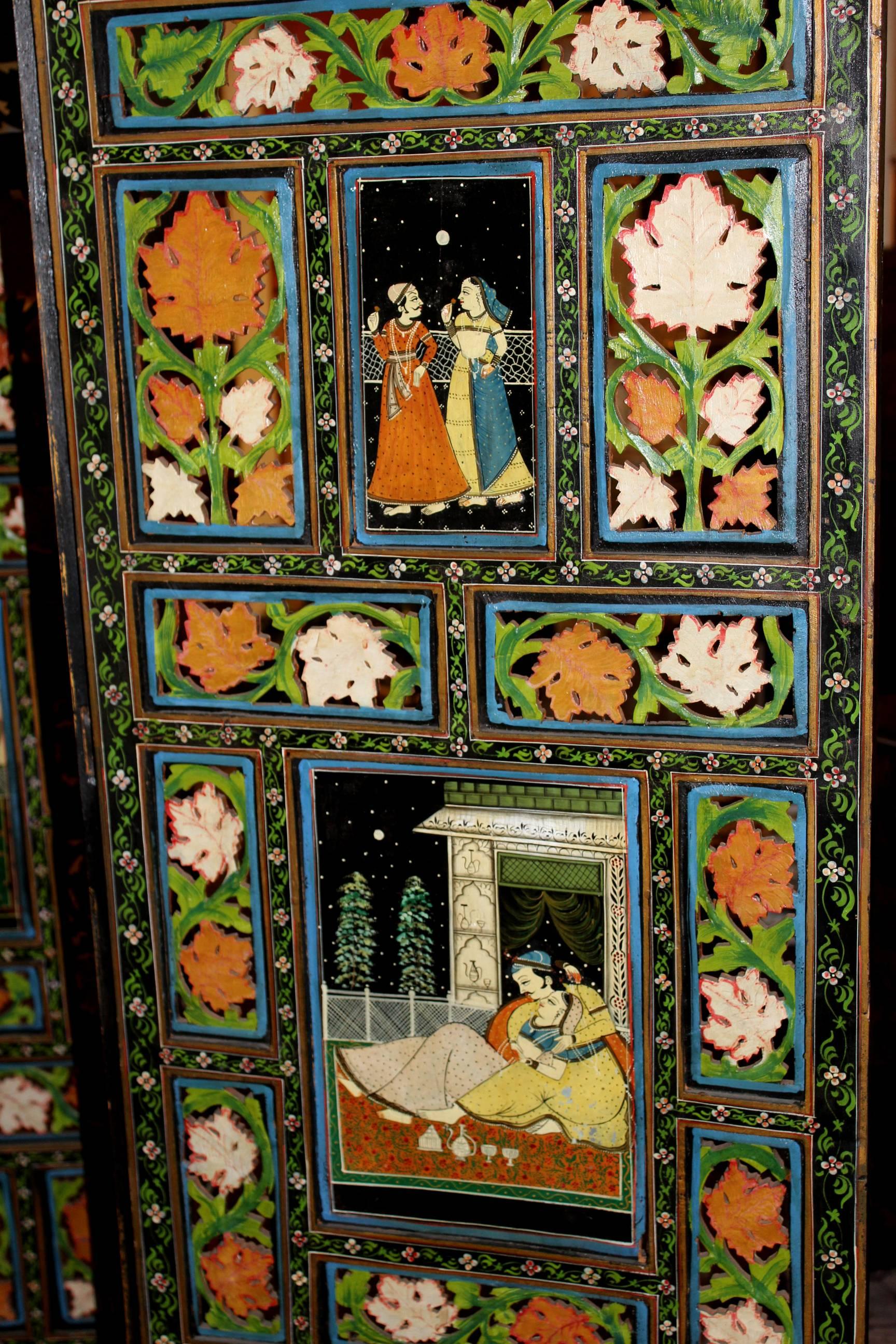 A polychrome hand-painted Indian wooden dressing screen or room divider with four reticulated panels, each panel with a vibrant palette on both sides with painted panel figures, foliate decorated borders and removable shaped crest. Dates to the