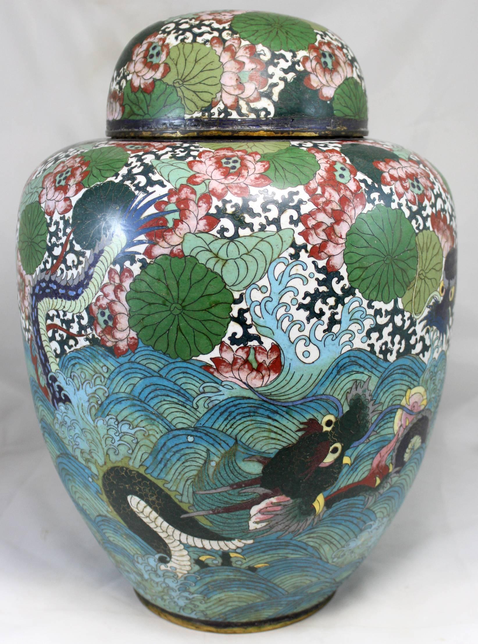 Large polychrome Chinese bronze or brass and hand-painted enamel cloisonné covered jar or urn with sea serpent decoration, as well as a variety of foliate decorations on the upper half and cover of the piece. Hand signed on base. Probably dates to