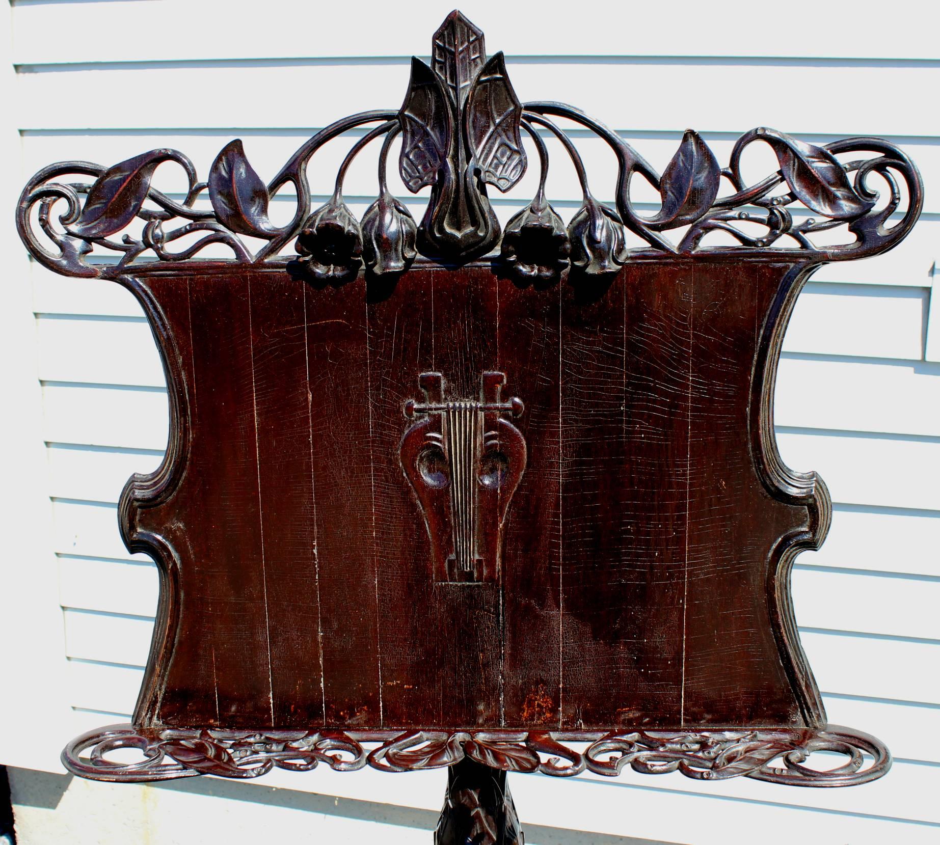 An exceptional example of a Victorian or Art Nouveau music stand with centre carved lyre motif, pierce and foliate carved crest and shelf, adjustable height stand with foliate decorated shaft and tripod base. The music shelf has adjustable brass