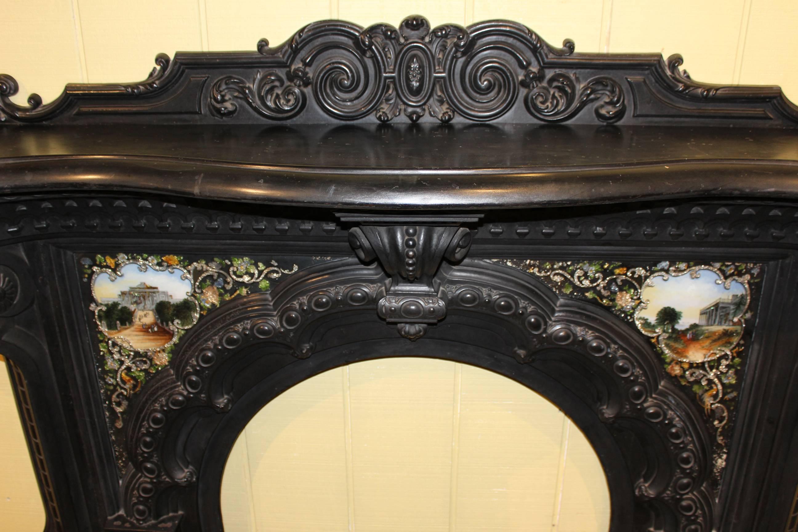 An exceptional cast iron fireplace serpentine form mantel and surround, circa 1850-1860, with original inset églomisé glass panels depicting buildings and figures, attached Rococo backsplash, central arched interior opening, and large scrolled