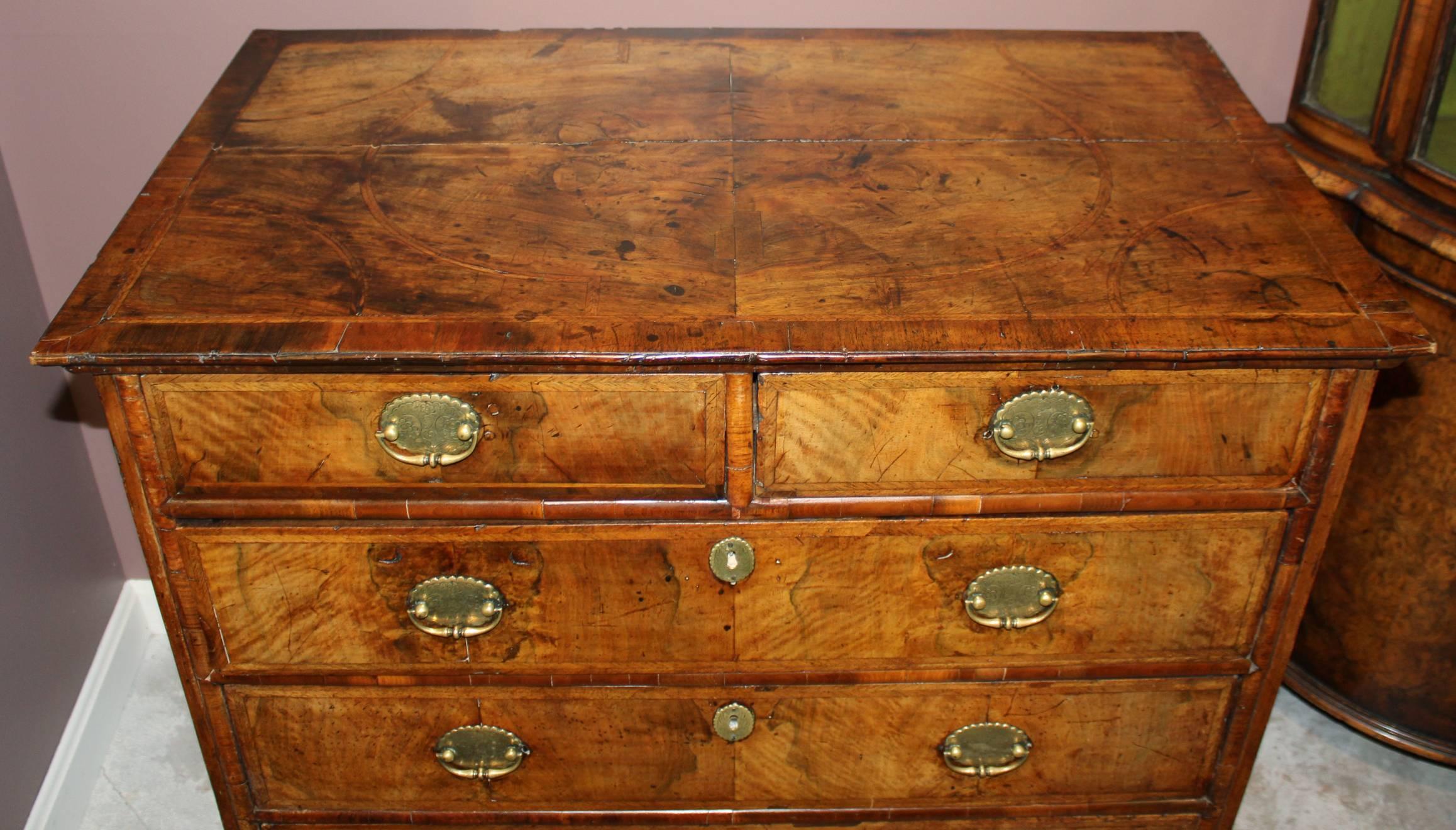 A fine example of a William & Mary four drawer chest in walnut, with quarter veneered top with feather banded drawers all raised on restored bun feet. The brass pulls are18th century but not original, and the escutcheons appear original. From a