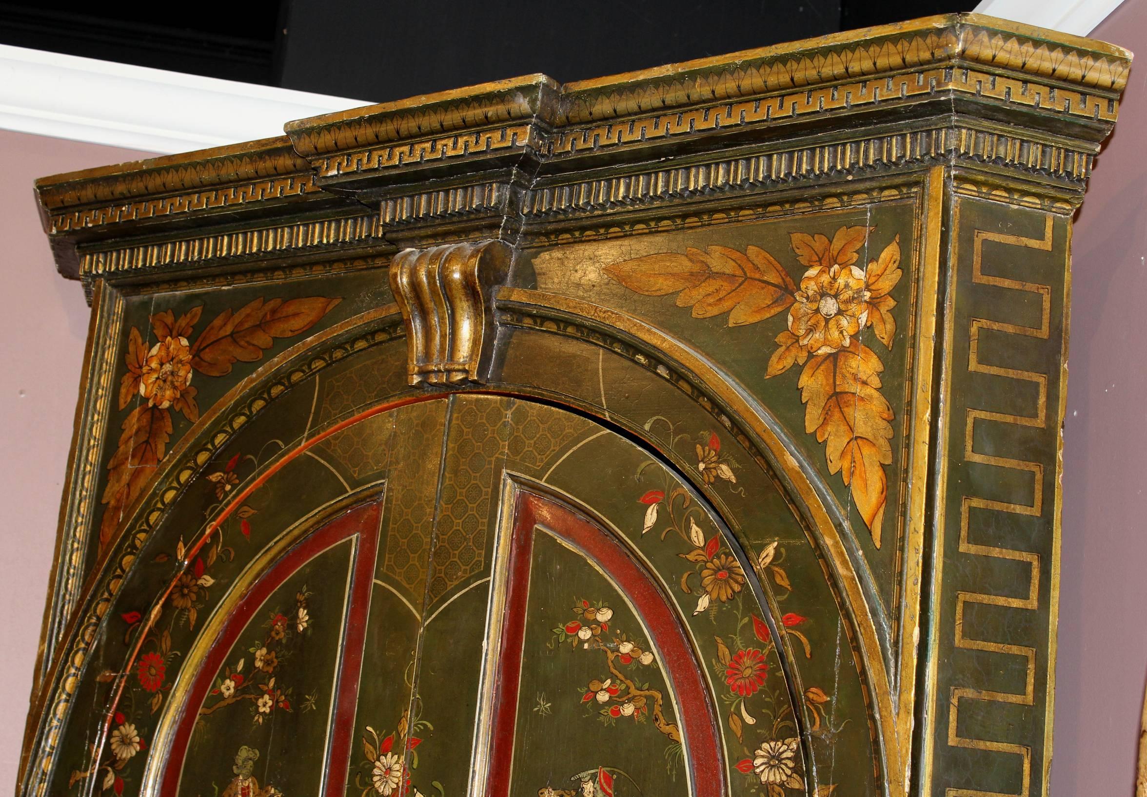 An exceptional George III polychrome two-part corner cupboard with chinoiserie decoration including men on horseback, other walking figures, flowers and birds, primarily in olive green, red, and gilt colors, with a geometric carved cornice, an upper