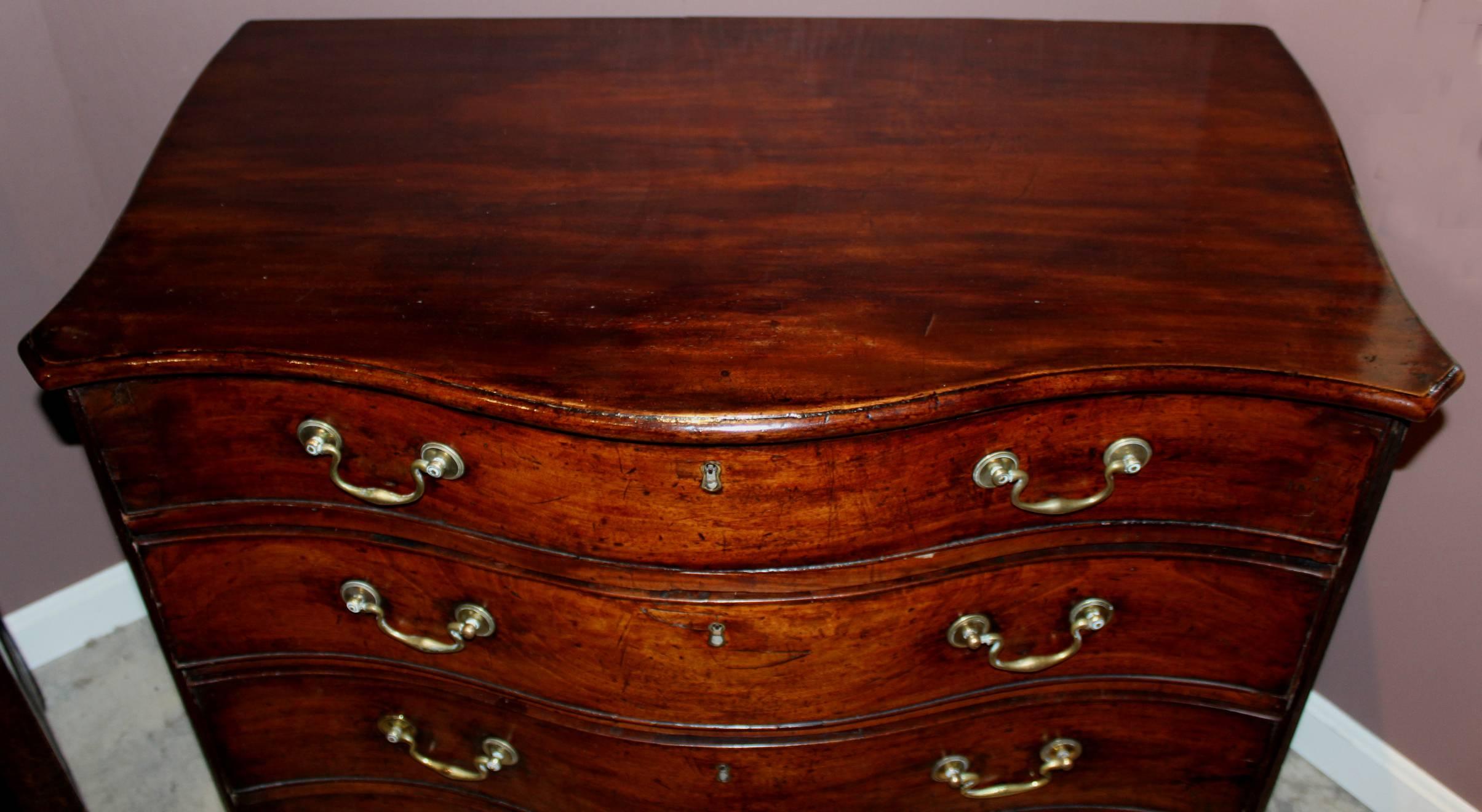 A fine Georgian mahogany serpentine four drawer chest with conforming molded edge top over four graduated drawers flanked by canted reeded corners, side case handles, all supported by four bracket feet. Dates to the 18th century.
Very good to