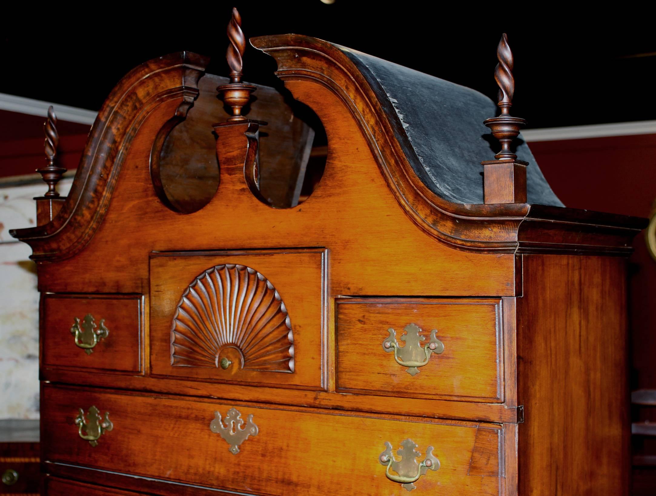 A splendid 18th century Queen Anne two part maple bonnet top highboy with bonnet top, flame finials, an upper case with three fitted small drawers over three graduated long drawers, the central upper fitted drawer with a radiating fan carving, over