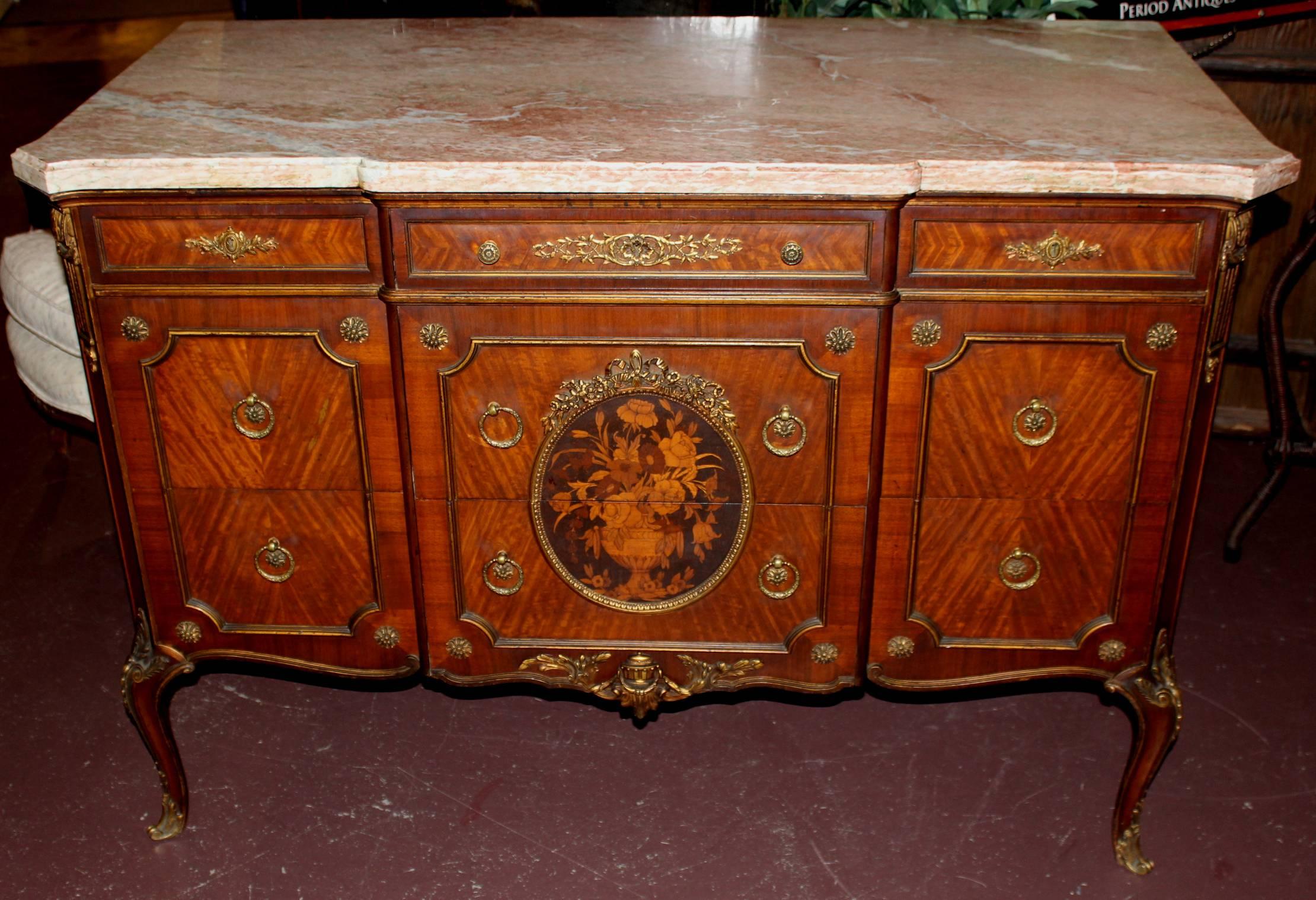 A splendid Louis XV style kingwood parquetry commode or chest with fitted rouge marble top, over a case with ormolu and rosettes the chamferred corners flanking three small drawers over six drawers with ring pulls, rosettes and centred by an oval