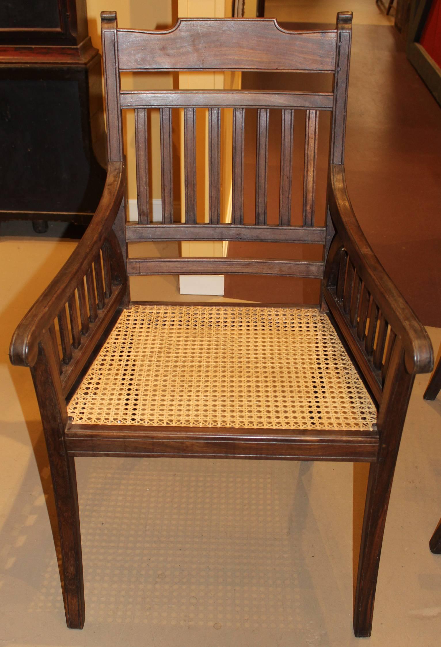 A fine pair of Regency style Anglo-Indian Colonial hardwood arm chairs with scroll end arms, slat backs, and freshly caned seats.