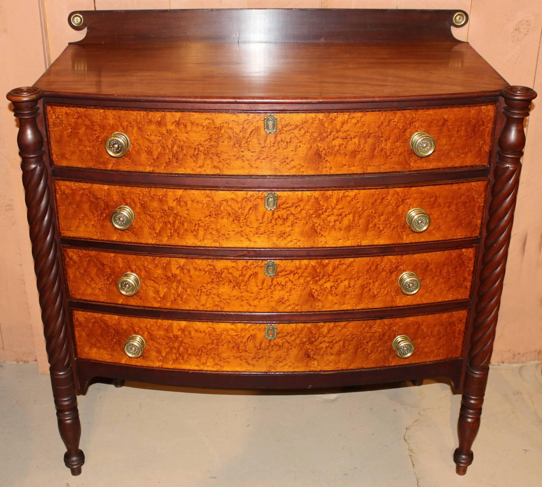 A splendid Federal Sheraton mahogany bow front chest with shaped backsplash with brass bulls eyes, a shaped top with turret corners over a conforming case with four graduated drawers, each with bird's-eye maple cockbeaded drawer fronts, flanked by