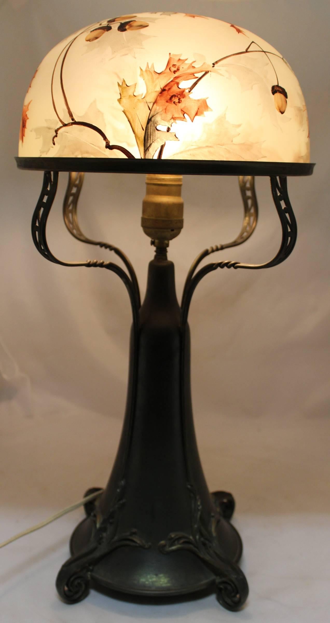 A splendid Art Nouveau table lamp with signed Pairpoint frosted dome shade in a polychrome hand-painted oak leaf and acorn motif in earth tones, supported by four twisted and pierced arms on a scroll footed brassed metal base with great patina. The