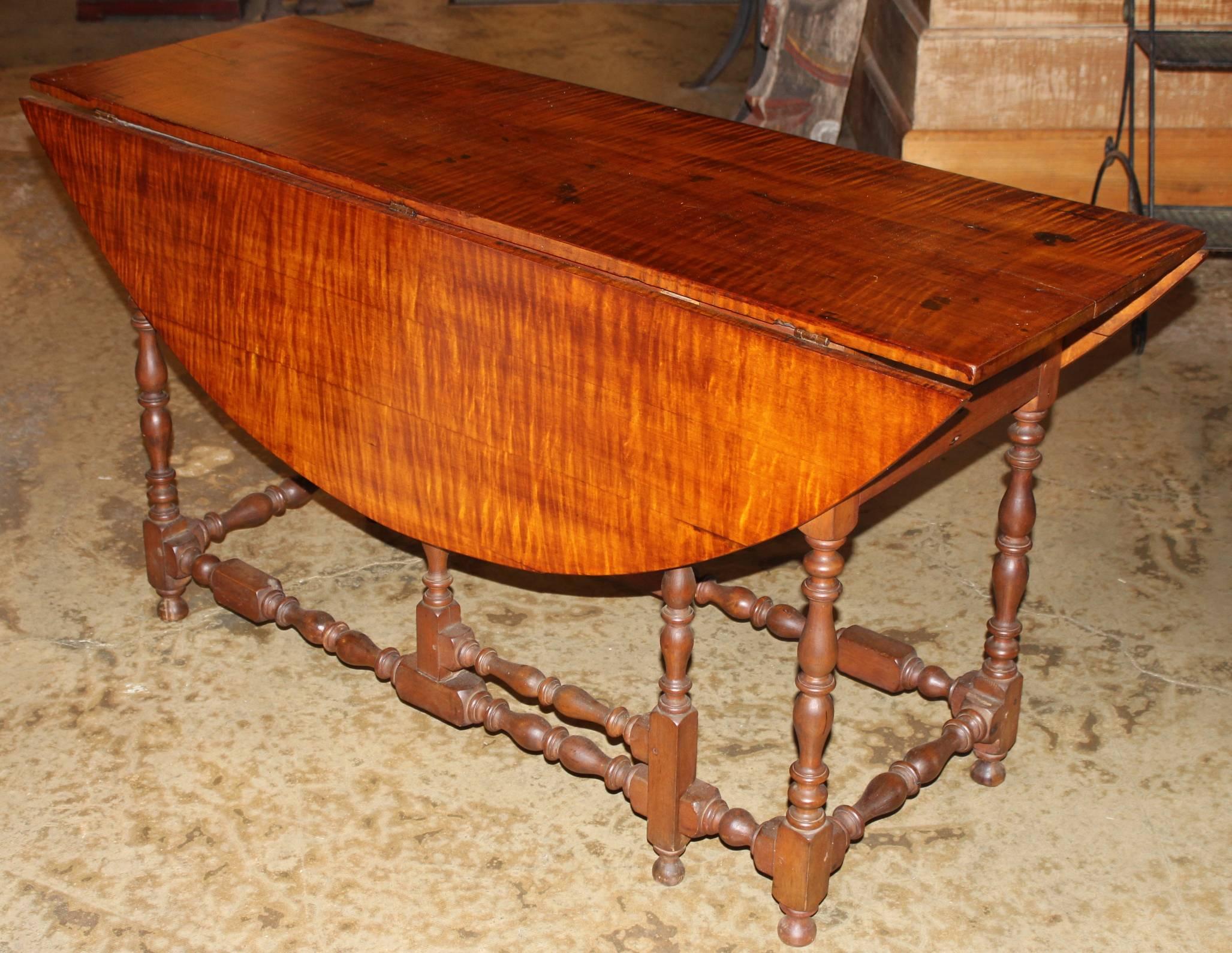 A 19th century adapted William and Mary style American gate leg table with striking tiger maple oval top with nicely turned gate legs and a fitted drawer on each end, in very good overall condition, with restorations, some minor losses and
