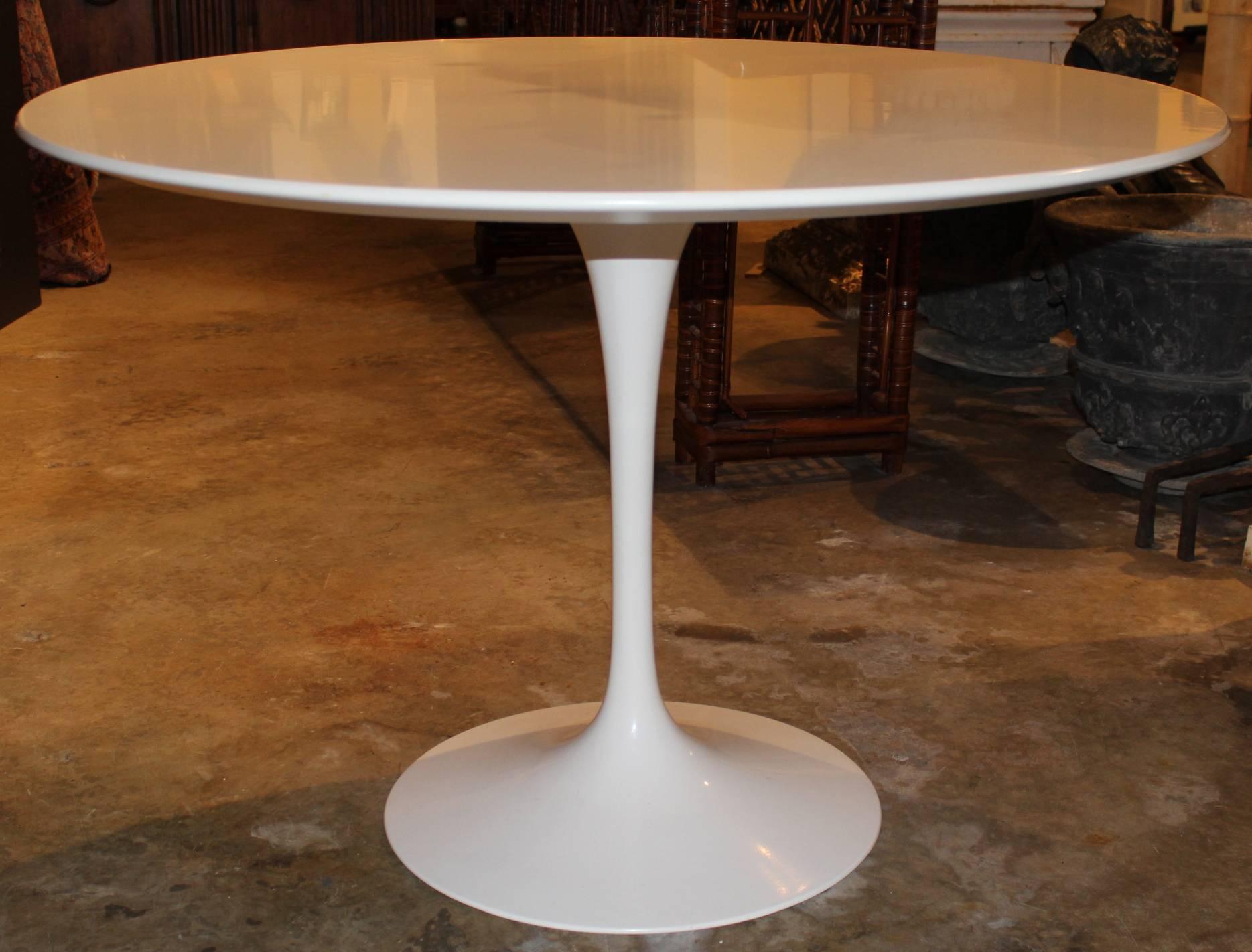 A fine example of a Mid-Century Modern style laminate round dining table with white painted cast aluminium base, with four molded fiberglass padded tulip armless chairs with aluminium bases designed by Eero Saarinen for Knoll International. Embossed