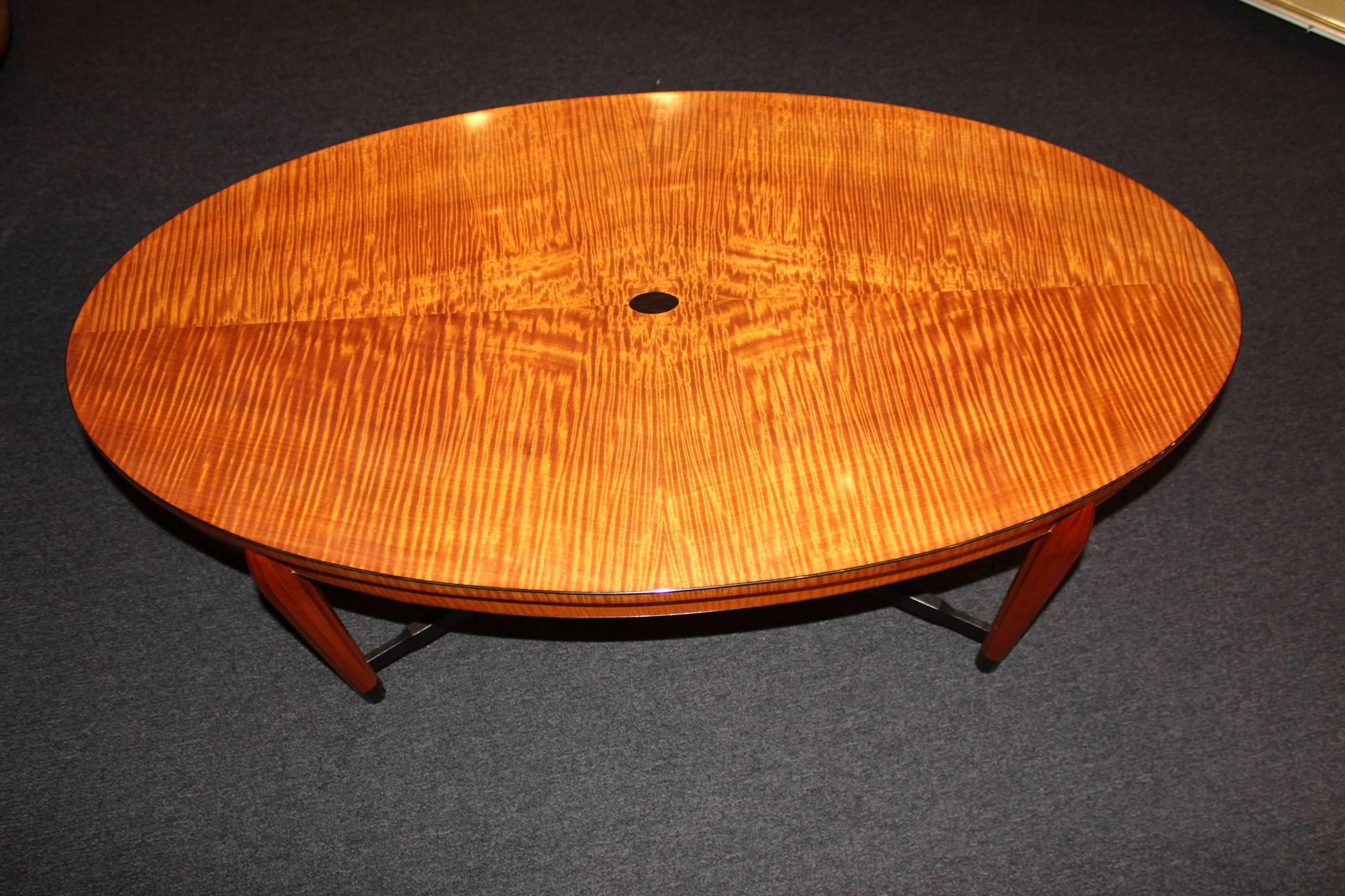 A fabulous handcrafted tiger maple veneered oval coffee table with oval medial raised shelf, supported by ebonized stretchers and vertically carved tapered legs the table is highlighted with an ebonized trim and feet, and protected with a high gloss