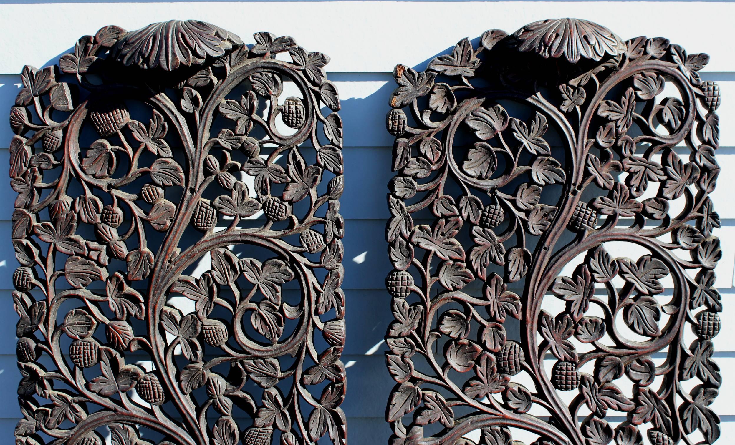 A fine pair of Asian foliate, pierce carved rectangular hardwood panels, probably dating to the 19th century, with an overhanging leaf crest on each, and great overall patina on their original dark finish. These panels were once probably from a