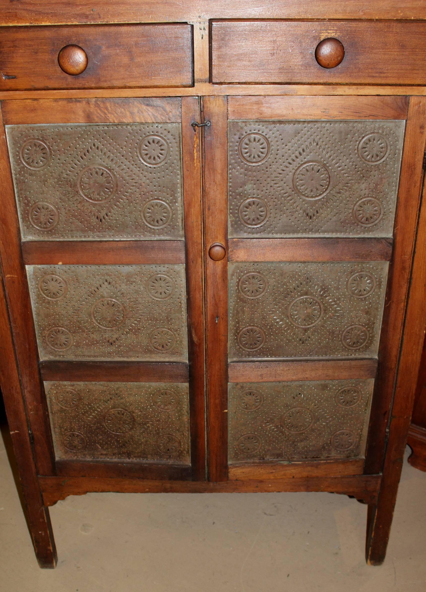 A fine example of a pine two-door pine safe with two fitted top drawers over tin punch decorated panels on the doors and sides, and an interior with three interior wooden shelves, showing hints of original green paint inside. Very good overall