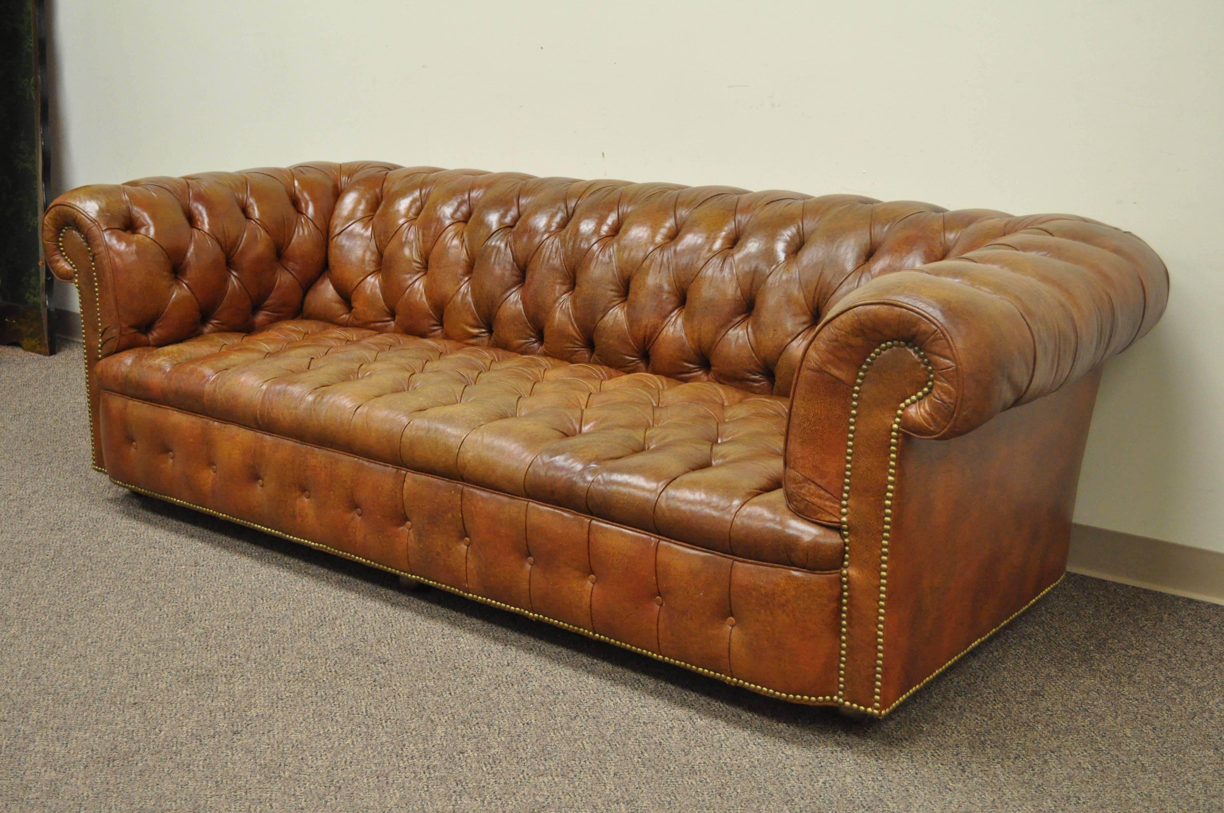 Vintage rolled arm English style button tufted brown leather chesterfield sofa by Henredon on rolling casters.