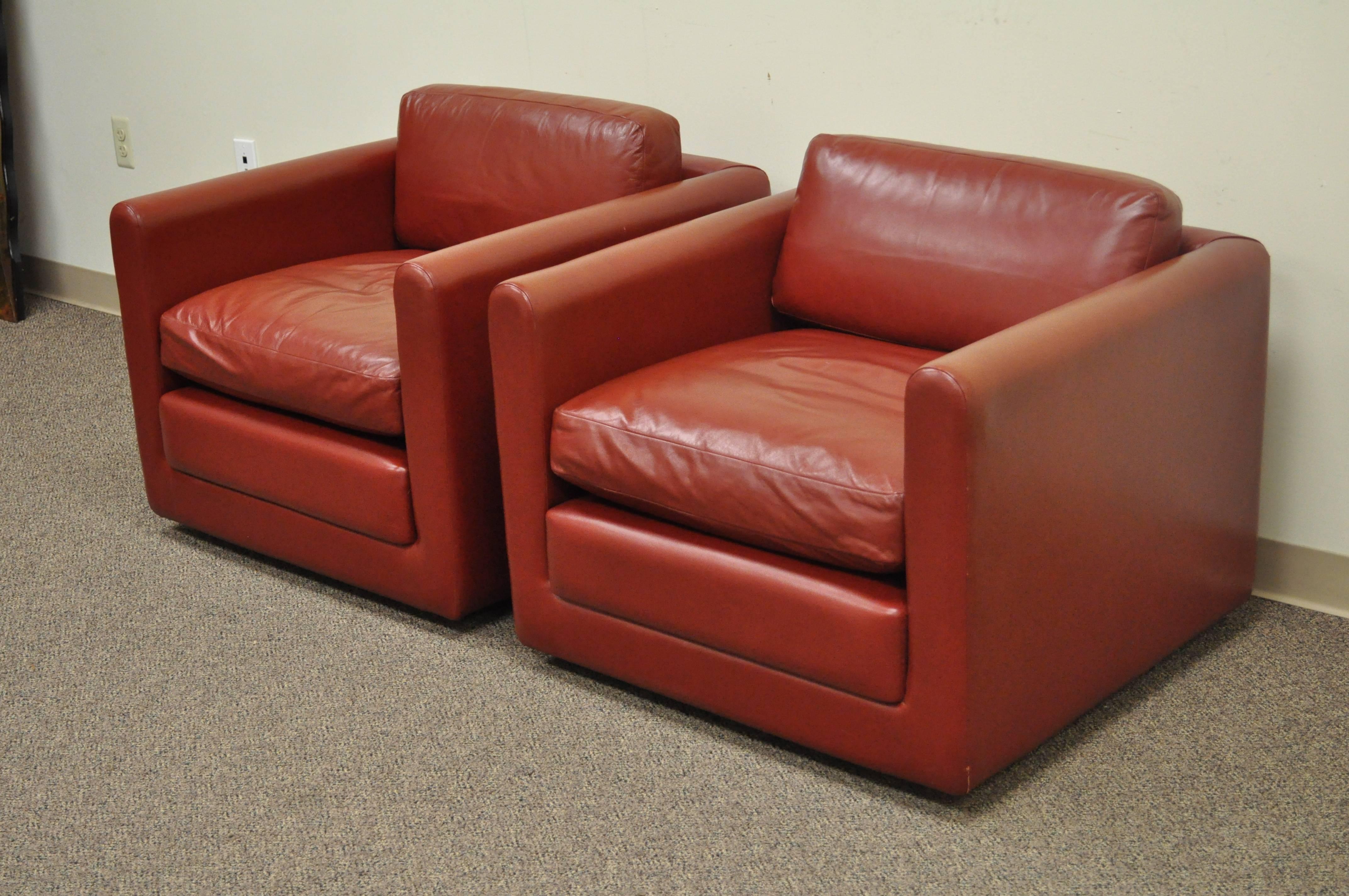 Quality pair of vintage, post-mid-century modern, cube form club chairs in red leather on rolling casters. The chairs features clean lines, comfortable form, solid frames, loose cushions, and great functionality. The maker is unconfirmed. Arm height