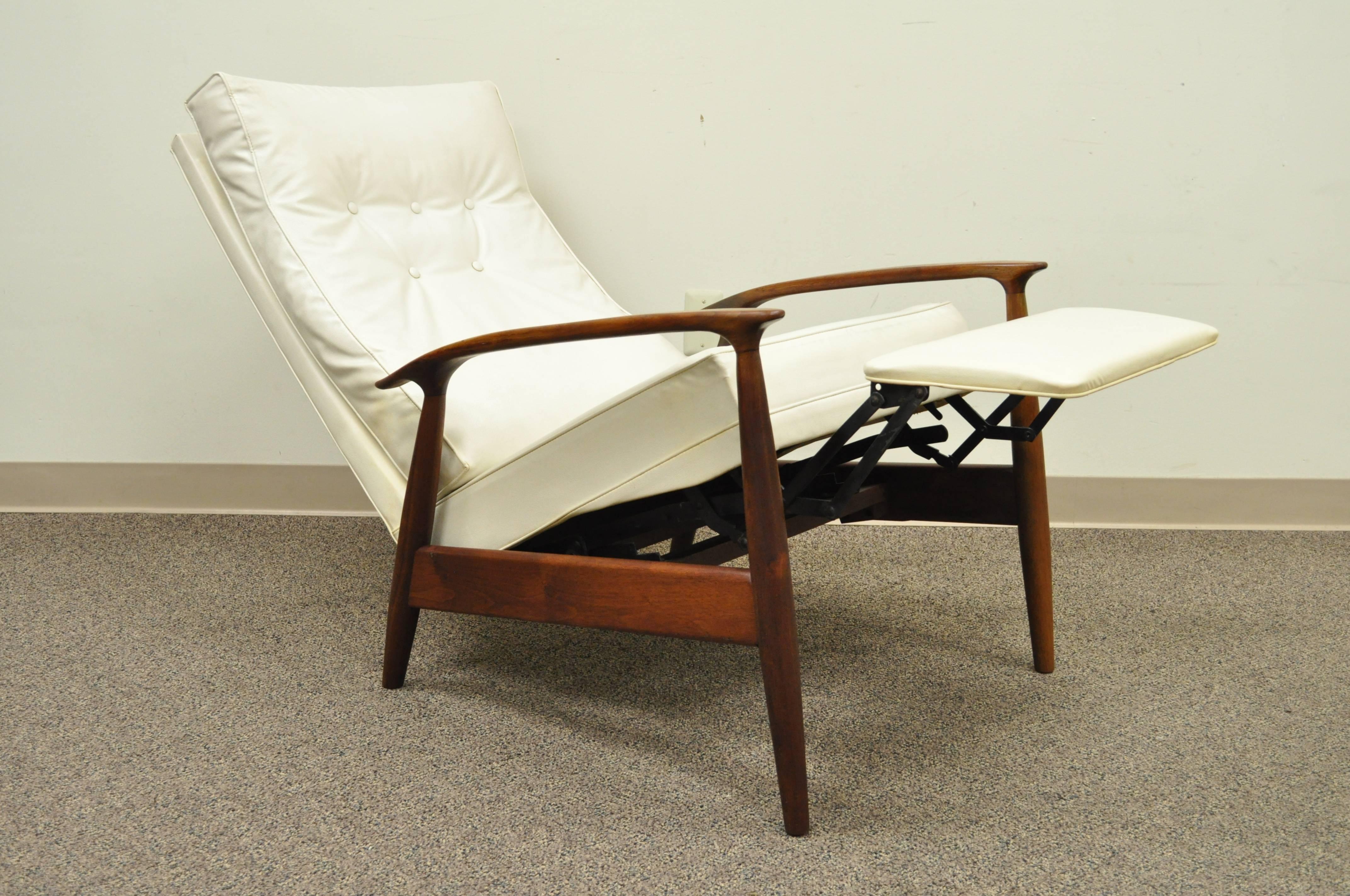 Early Milo Baughman designed sculpted frame reclining walnut lounge chair for James, Incorporated (An early division of Thayer Coggin). Chair features a very comfortable reclining position with flip out footrest and the original white vinyl