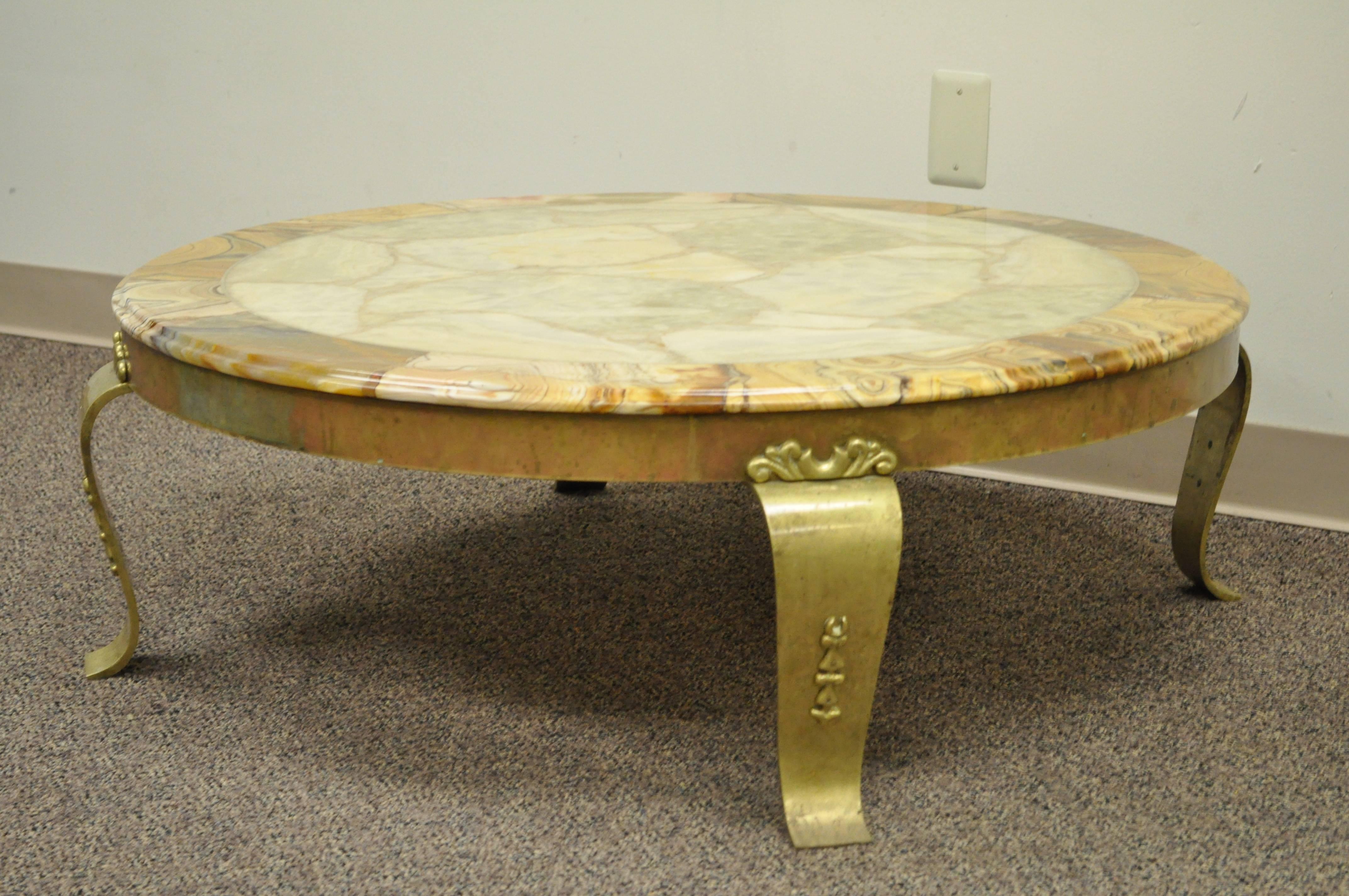 Stunning Hollywood Regency / Mid-Century Modern round coffee table by Muller. Item features a solid brass base with decorated scrolling cabriole legs and a beautiful onyx top with beveled edge. Brass is in original condition and has achieved a