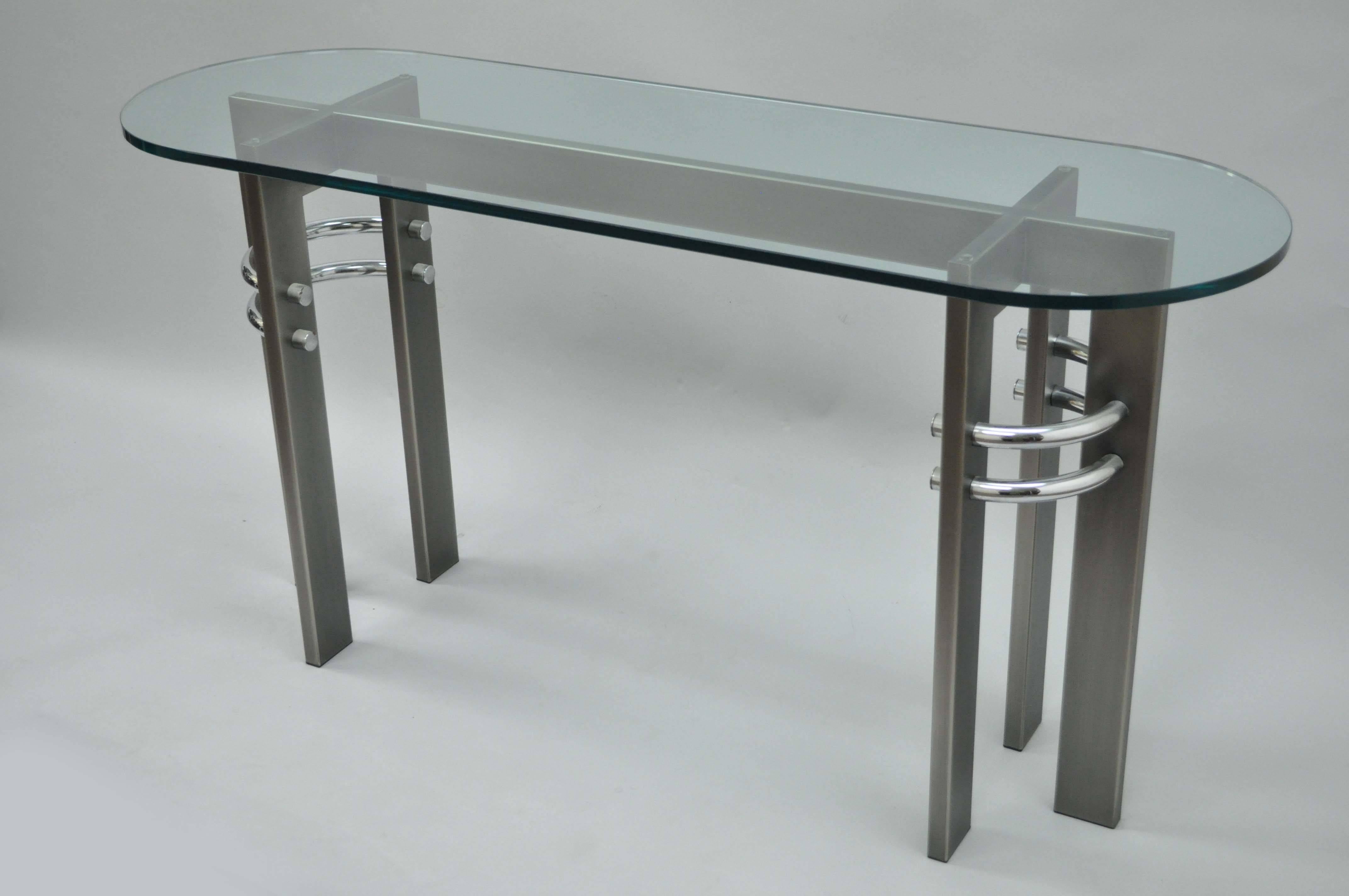 Contemporary or Memphis style brushed metal, chrome and glass console table design institute of America dia. Item features a thick oval glass top and unique sculptural base.