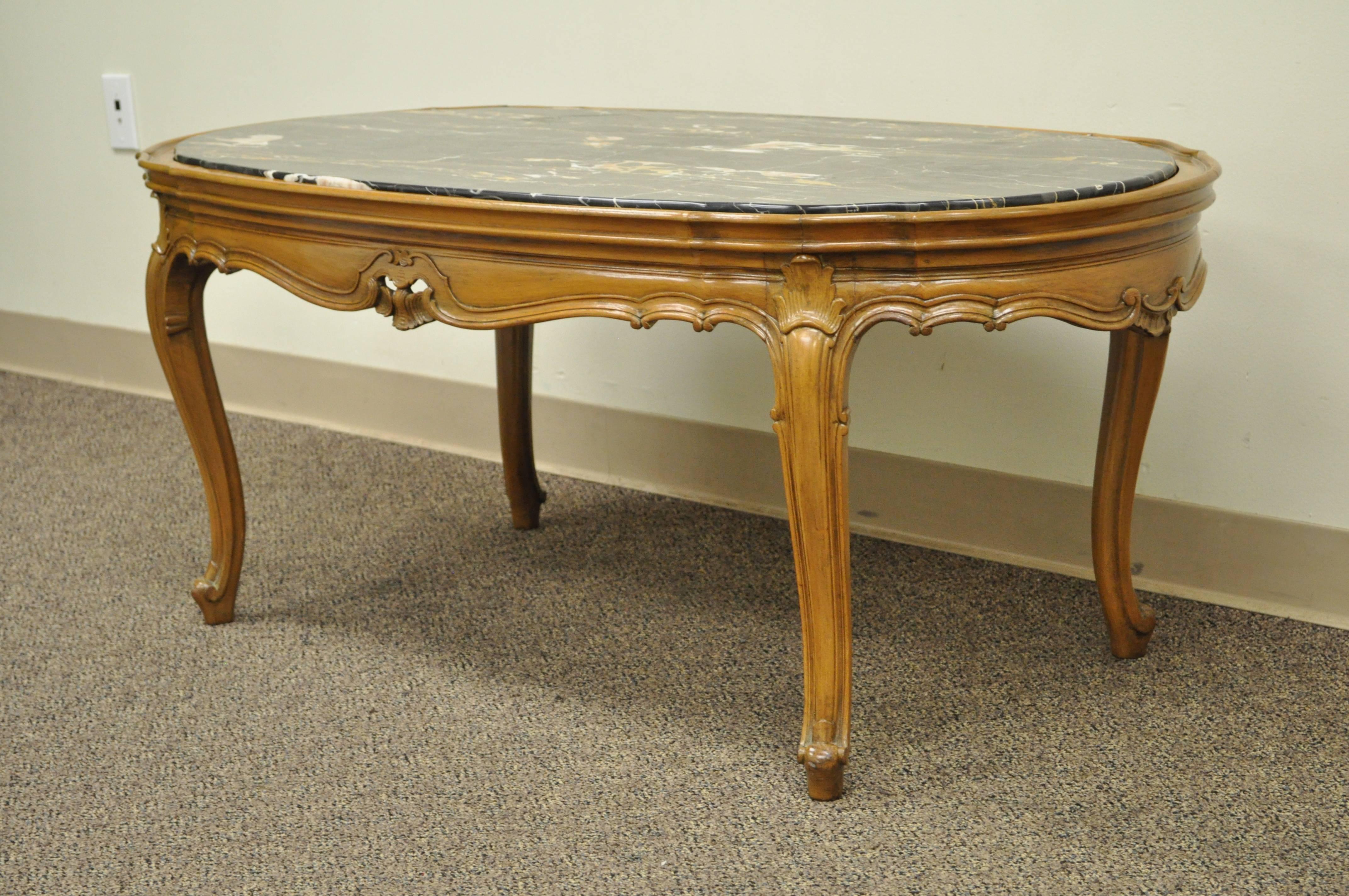 1930s French Provincial / Louis XV Country Style oval marble top carved walnut coffee table. Item features an inset marble top, carved walnut scalloped base, shell accents, and great quality. Item is stamped 