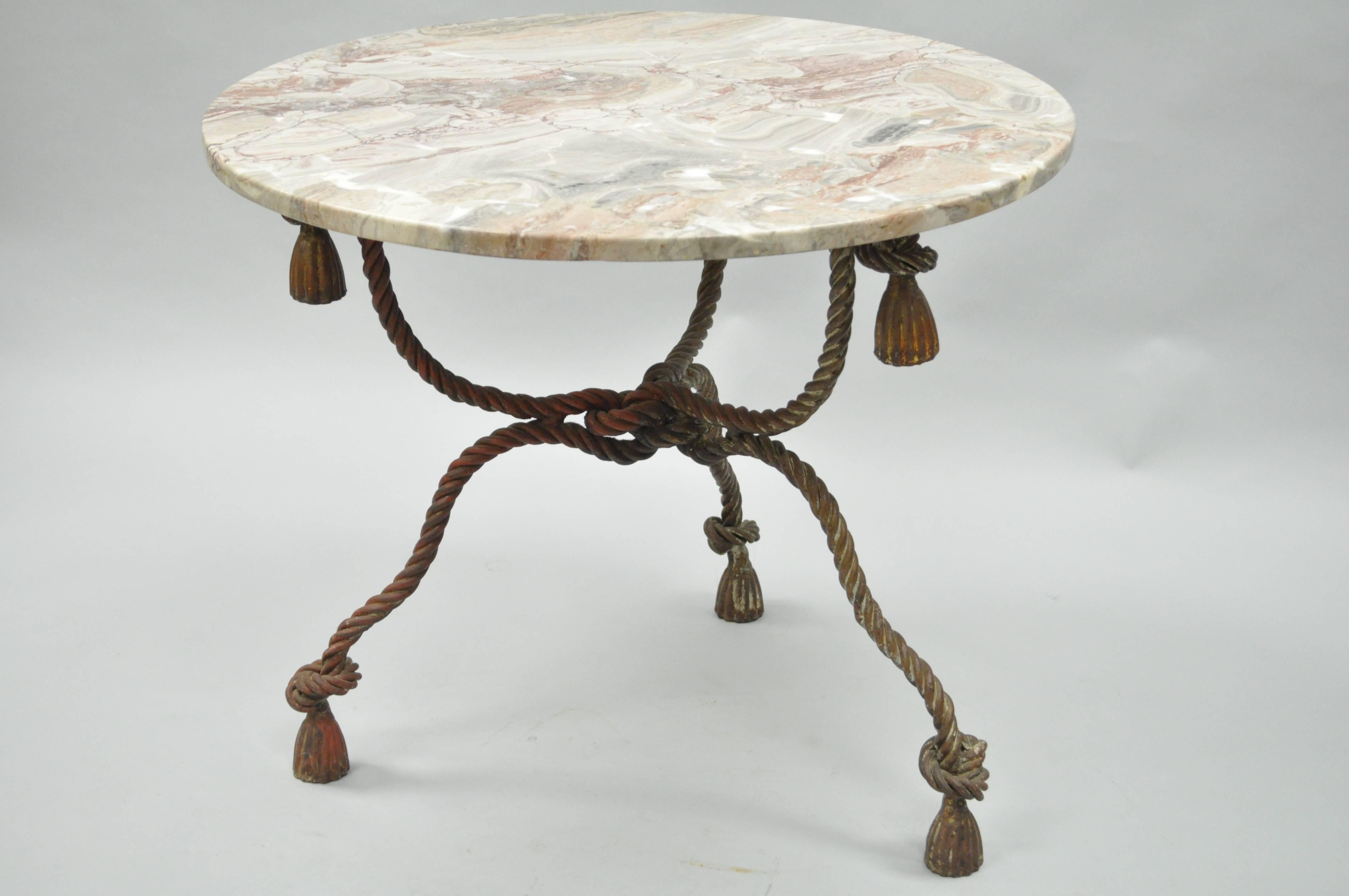 1940s Italian Hollywood Regency marble-top rope turned center table. Item features a pink accented round marble top, heavy rope and tassel form iron base with a desirable antiqued gold gilt finish. Stunning quality item. Stamped, made in Italy.