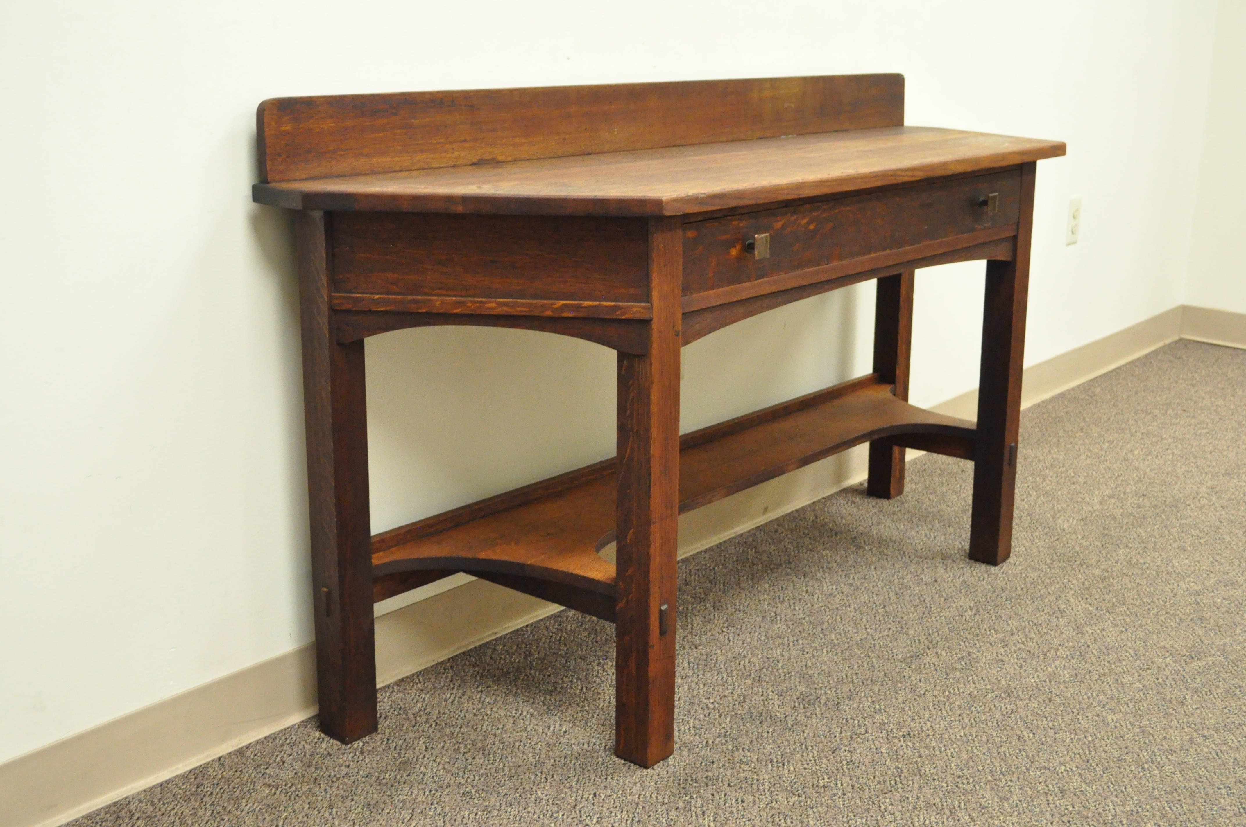 Very rare one-drawer mission oak console table by Limbert with backsplash, circa 1910, grand rapids, MI. Item features a single drawer, hand-hammered copper pulls, over a shaped skirt, exposed tenons, raised backsplash, and Limbert brand on the