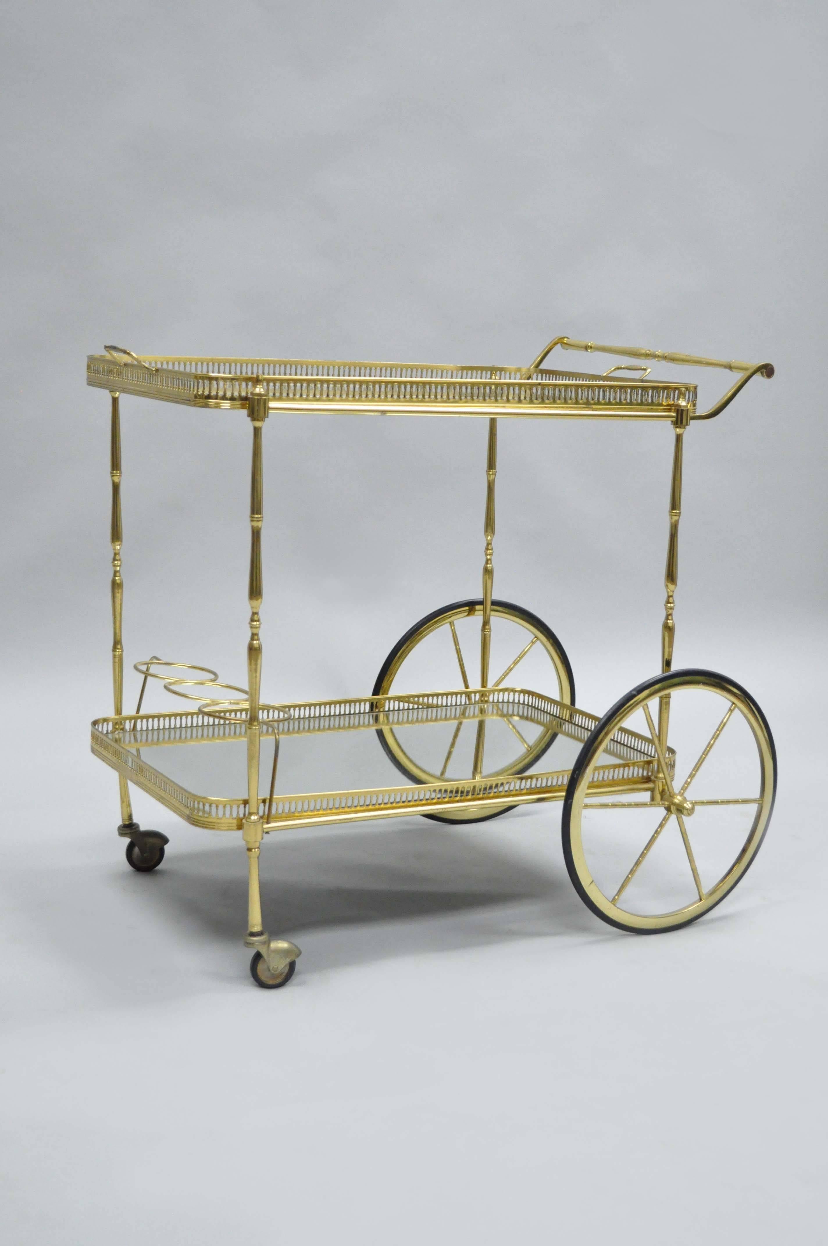 Quality Italian Hollywood Regency brass and mirror tea trolley. Item features a removable serving tray on the upper tier, pierced brass galleries, bottle holders and a solid brass frame. The upper tier of glass is clear in the center with mirrored