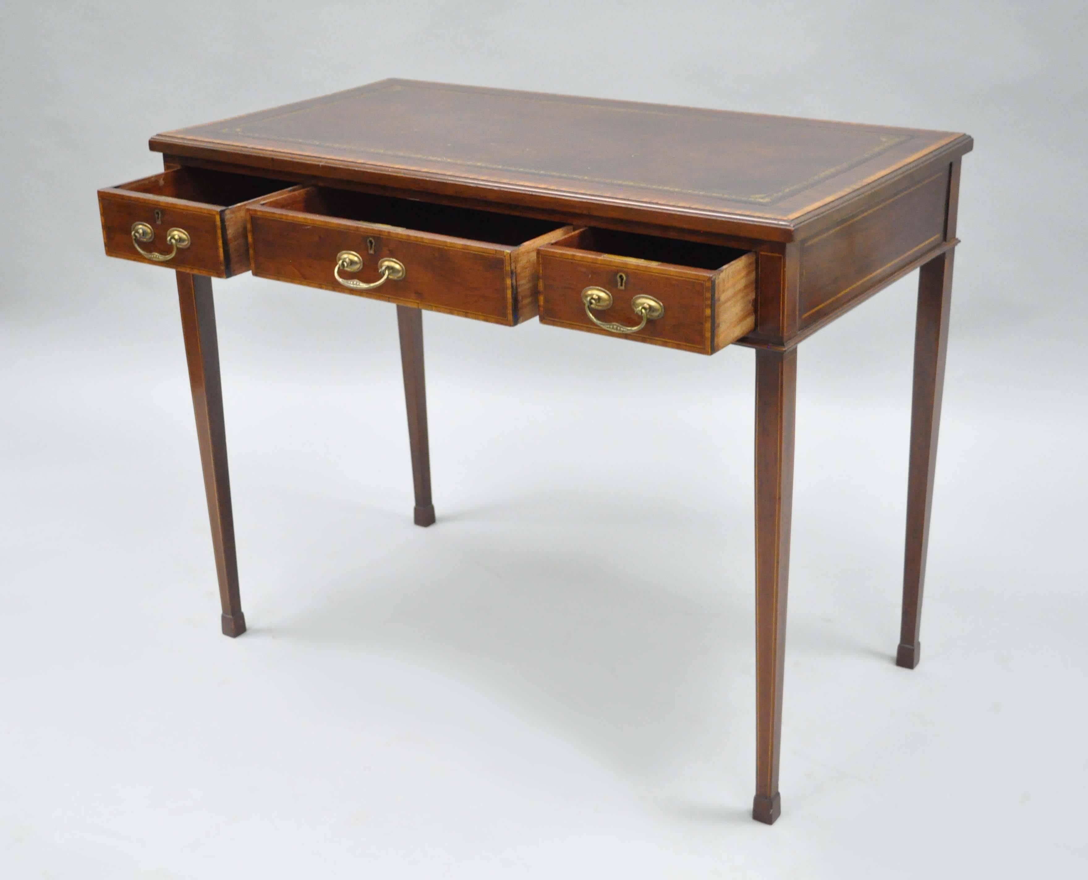 Remarkable quality early 20th century. Custom-made English George III style leather top petite ladies writing desk. Item features three hand dovetailed drawers, satinwood inlays, finished back, tooled leather and banded top, working locks with key.