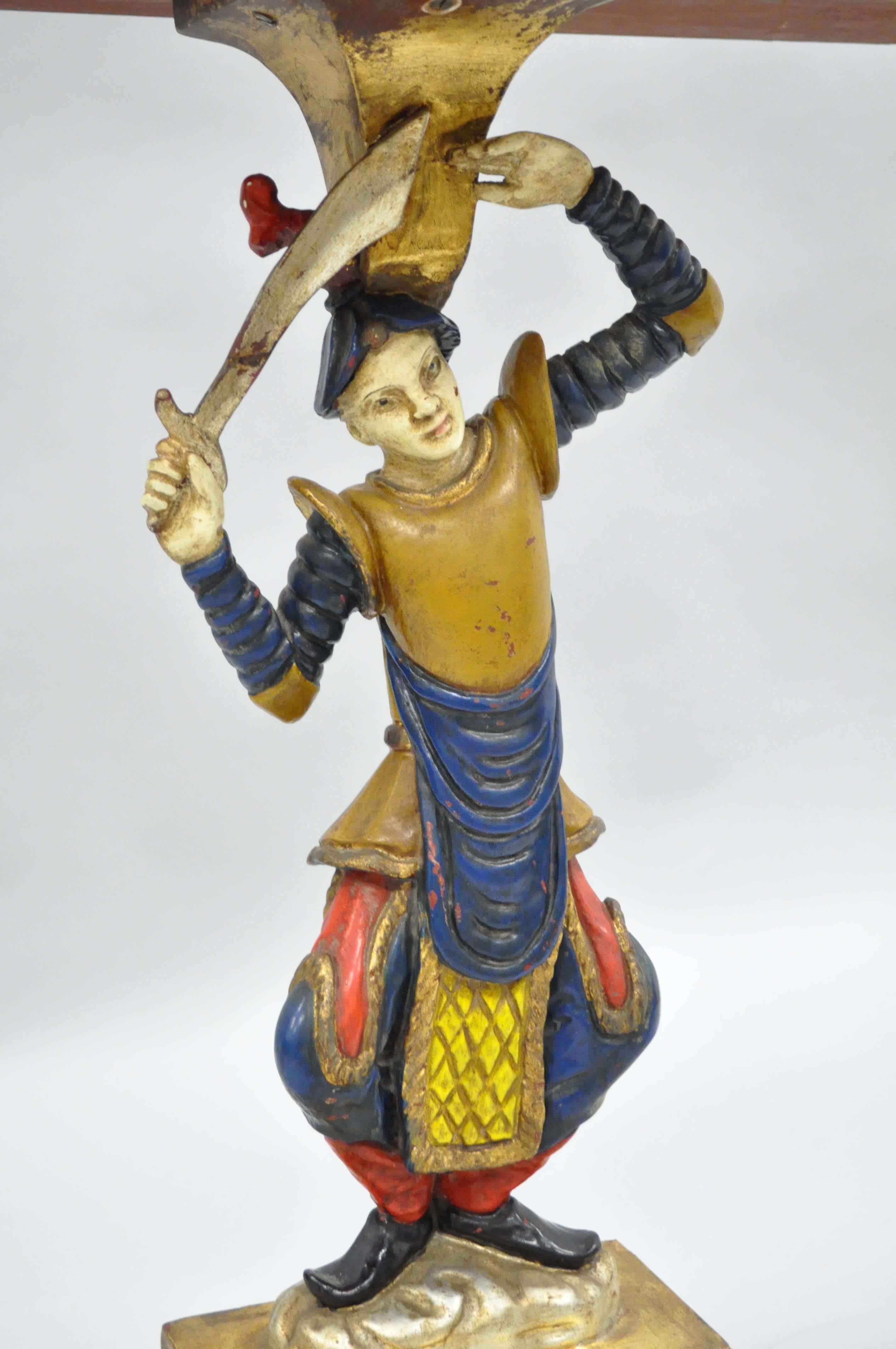 Very unique Italian Hollywood regency figural jester form table. Item is carved from solid wood with an antiqued gold leaf shaped top over a sword wielding jester form central support which rests on a raised platform base. The intentionally
