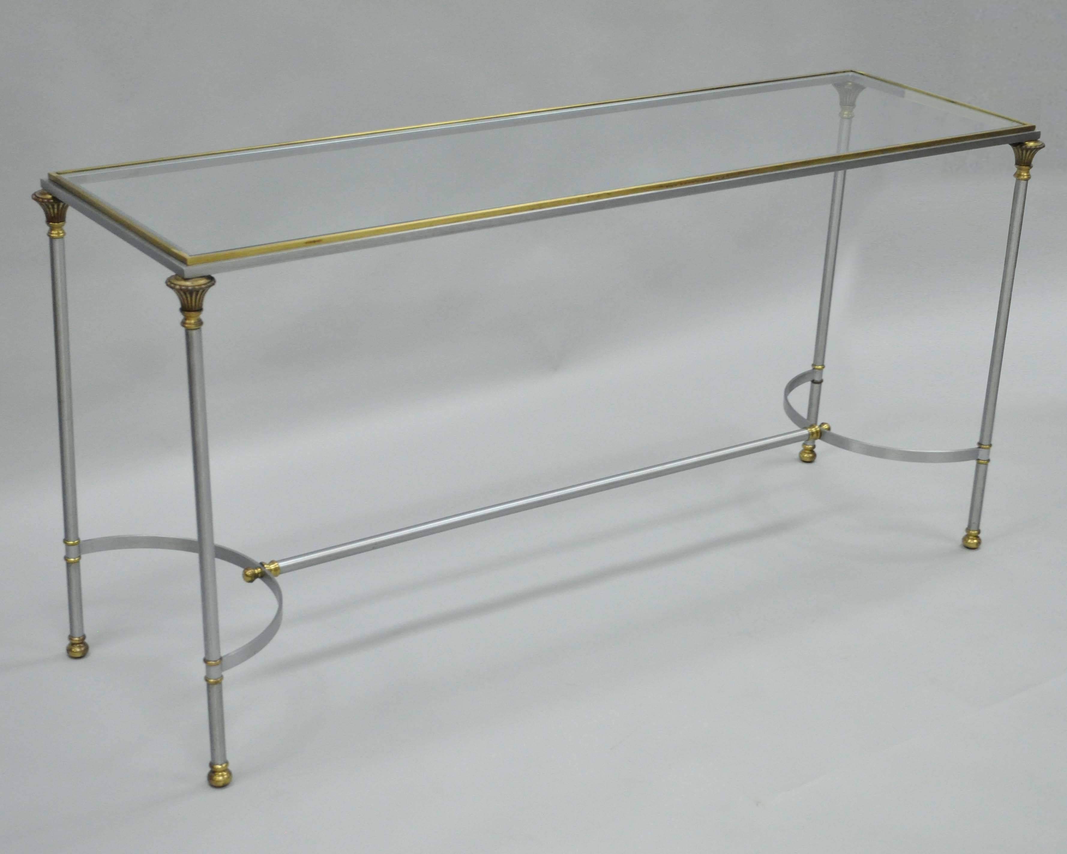 Elegant vintage Italian brushed steel and brass console table in the manner of Maison Jansen. Item features a rectangular form with solid brass gallery, inset glass top, brushed steel stretcher supported frame, brass accents and quintessential