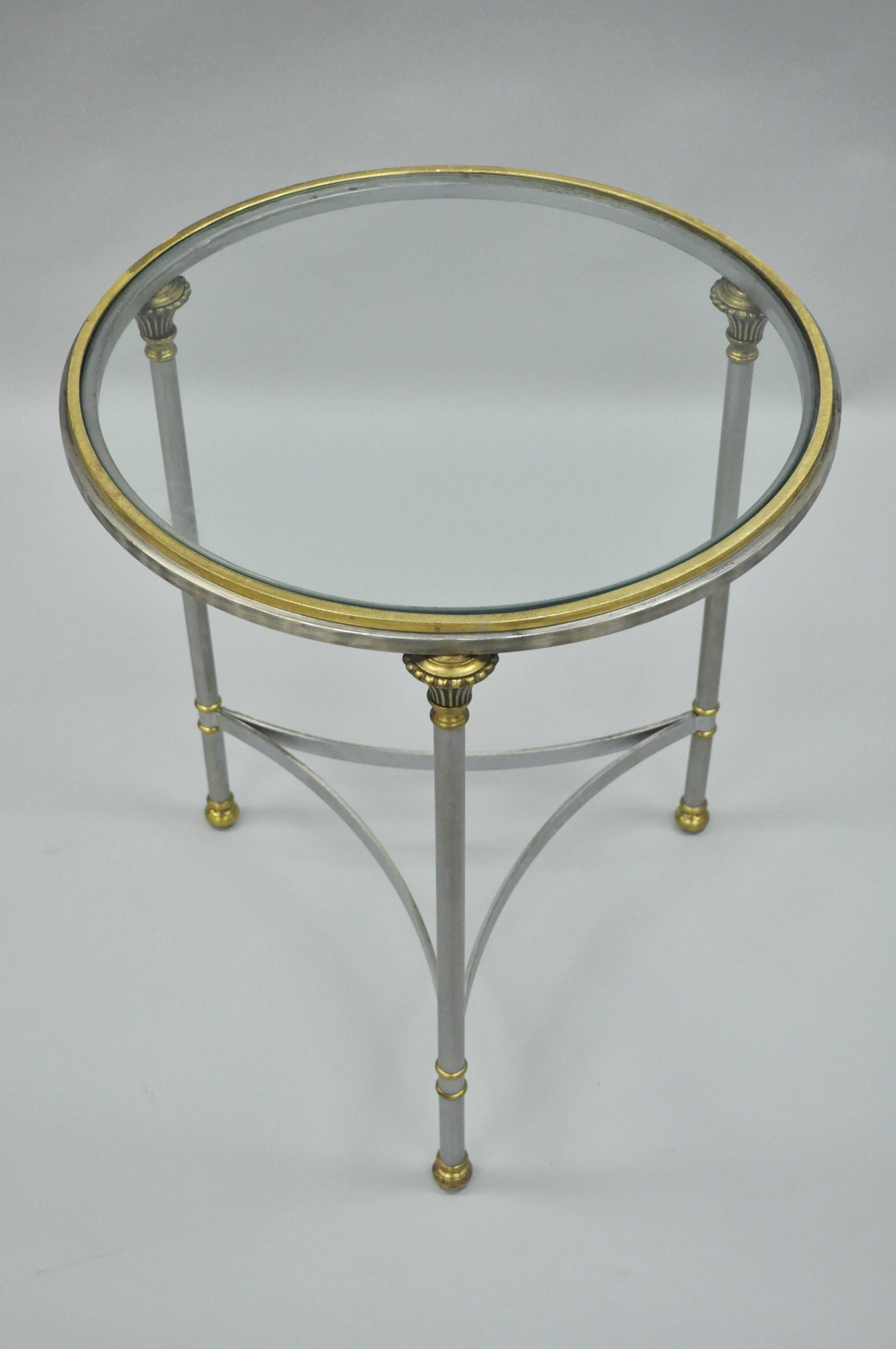 Elegant vintage Italian brushed steel and brass round accent table in the manner of Maison Jansen. Item features a round form with solid brass gallery, inset glass top, brushed steel stretcher supported frame, brass accents, and quintessential