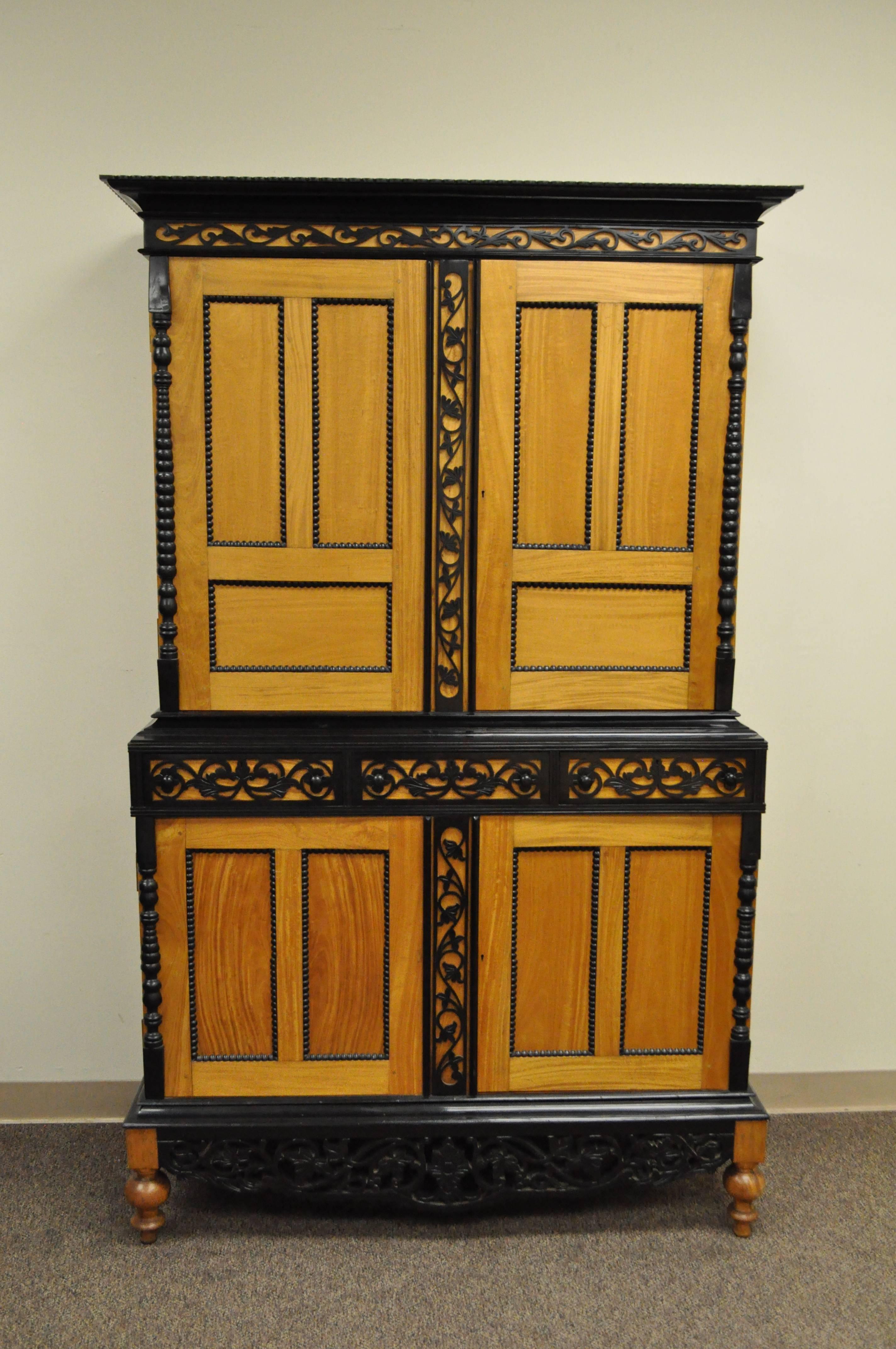 20th Century Indo Portuguese / Indo Dutch Colonial style cupboard cabinet. Item features beautiful satinwood, ebony, and mahogany wood, three dovetail constructed drawers, exposed pin joints, ornate pierced floral carved panels, three-part