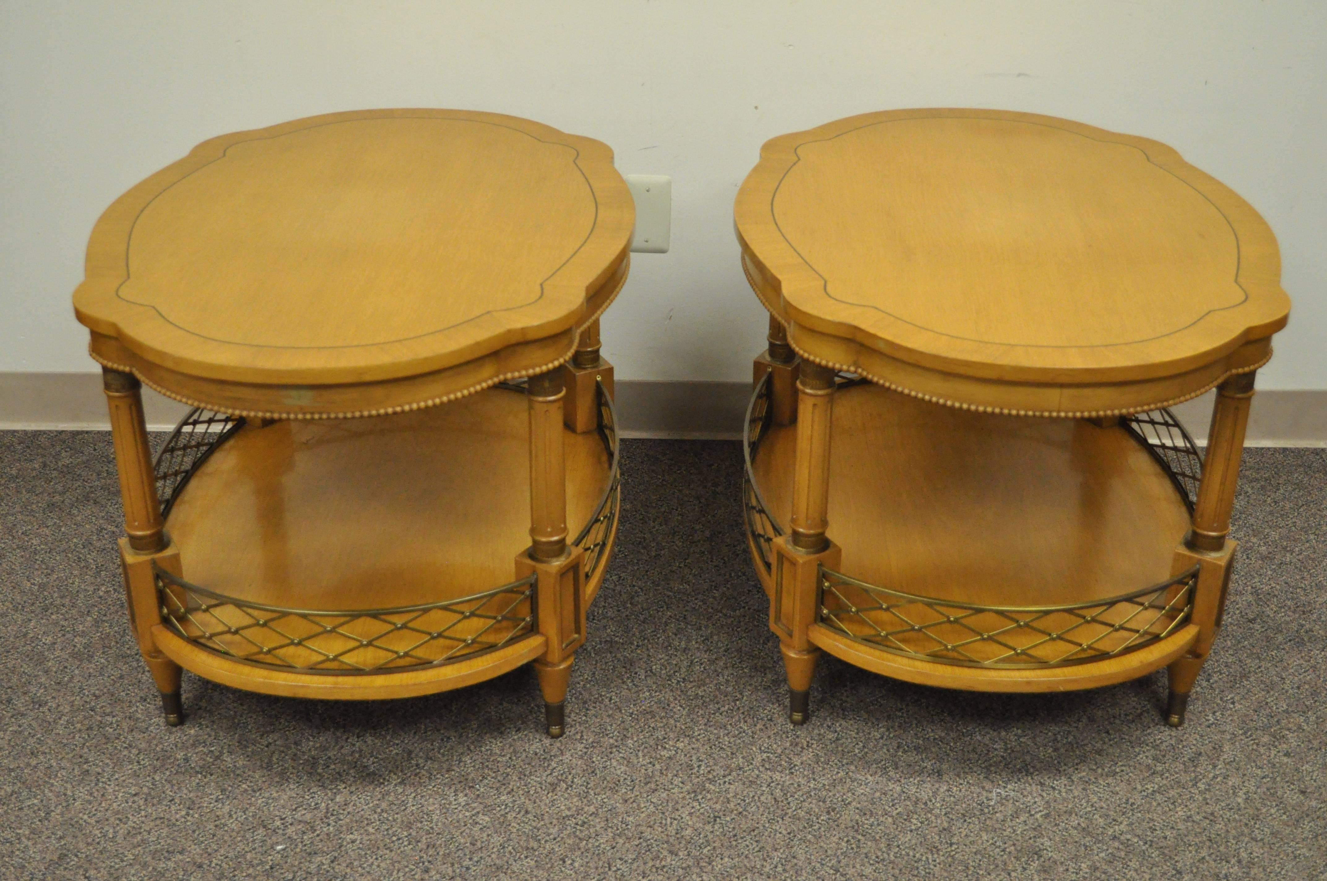 Quality pair of custom order vintage two-tier side tables with brass gallery, circa 1960s. Each table features a shaped banded top, beaded trim skirt, reeded column supports, crisscross brass lower gallery, brass capped feet and accents and elegant