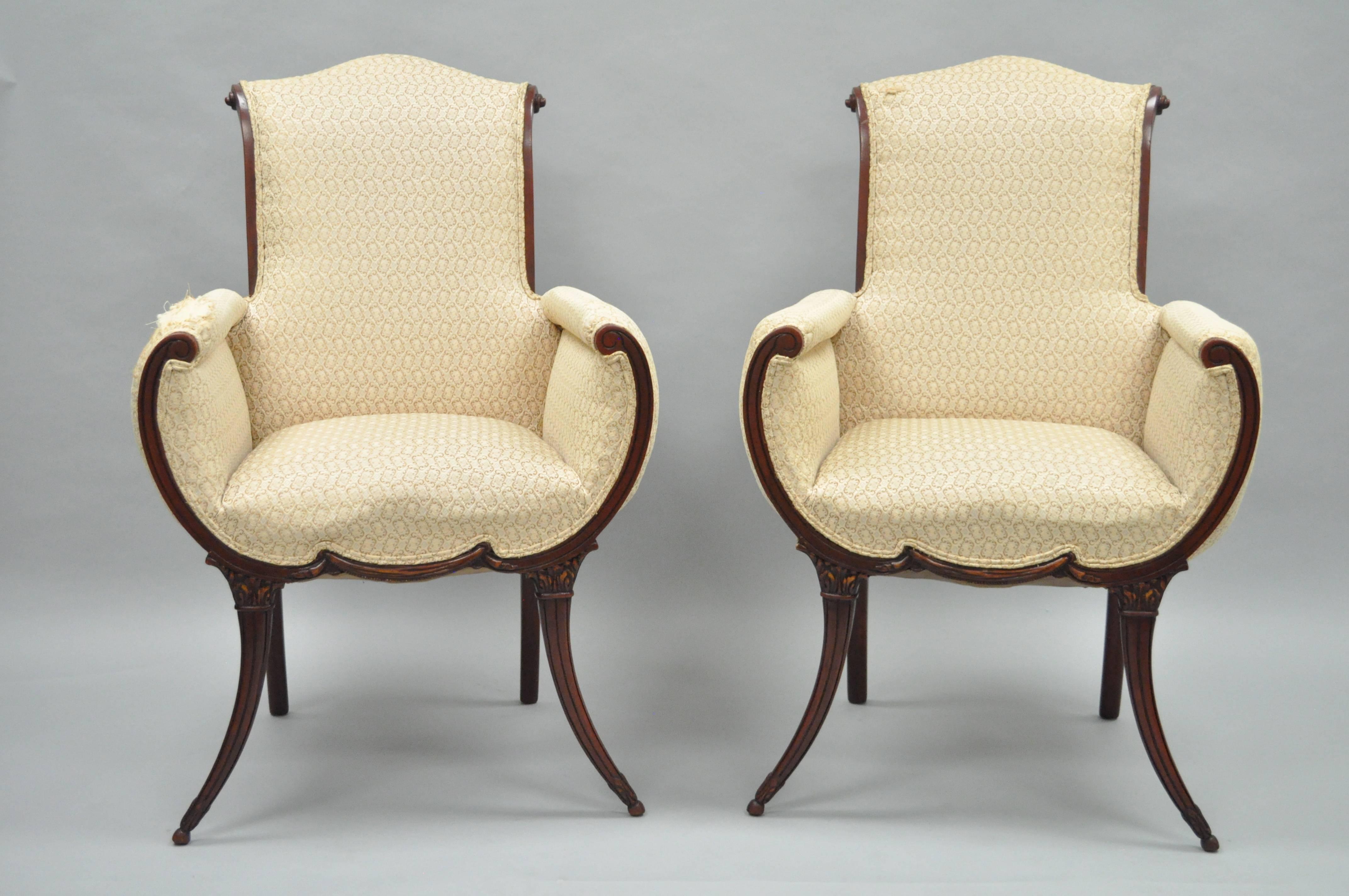 Stunning pair of 1940s saber leg fireside lounge chairs attributed to Grosfeld House. This elegant pair of armchairs features shapely solid mahogany wood frames, rolled backs, carved and tapered legs and front rail. The mahogany wood frame surrounds