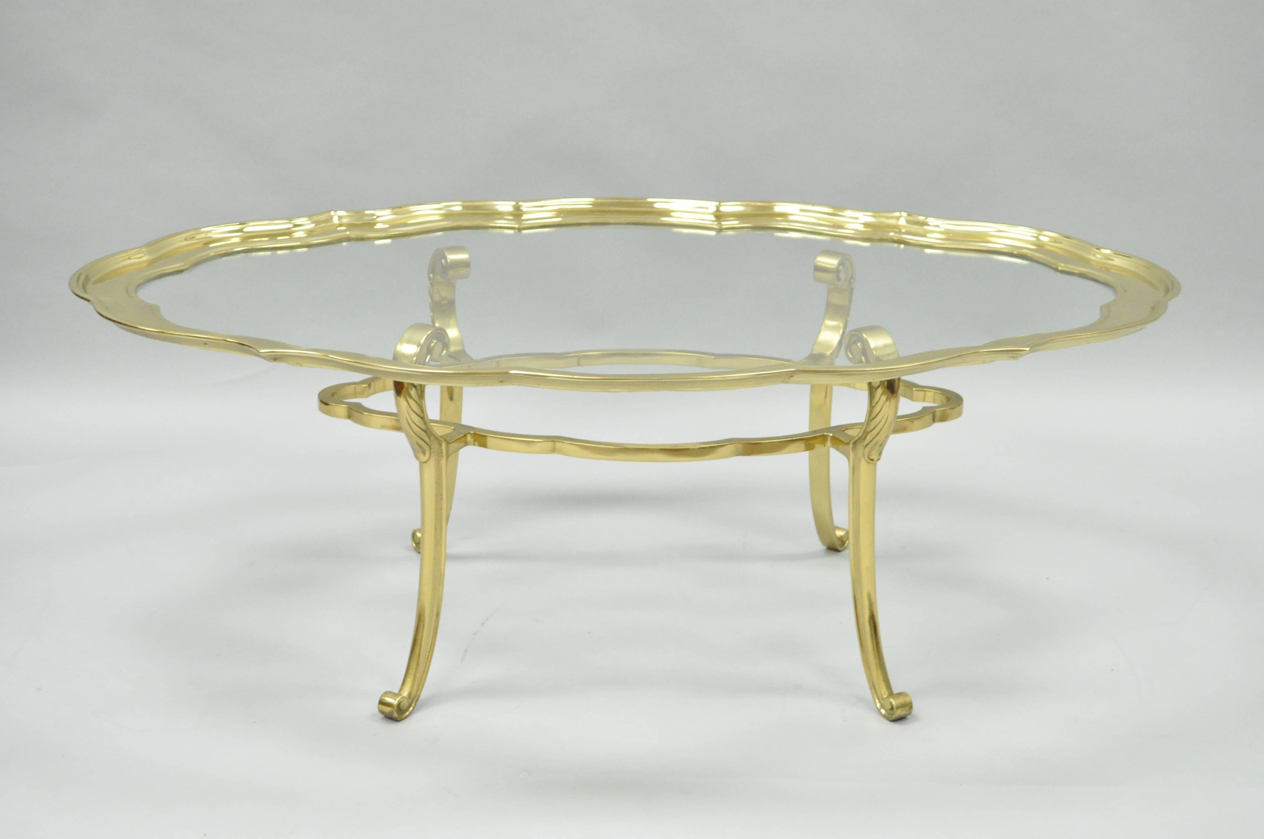 High quality vintage solid brass and glass serving coffee table attributed to Baker Furniture Co. This remarkable Hollywood Regency coffee table features a removable top with shaped solid brass border and glass center. The base is also solid brass