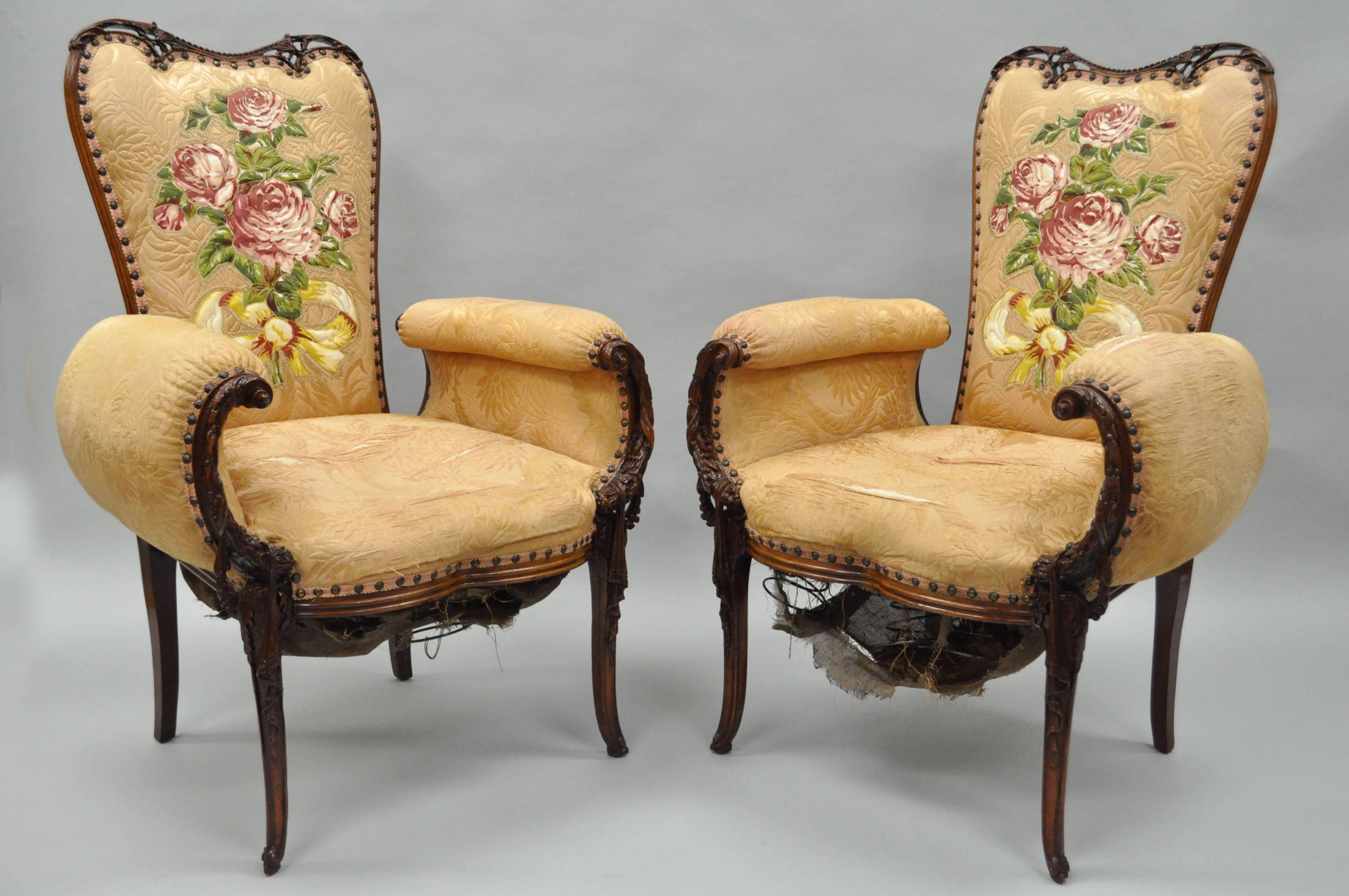 Stunning pair of 1940s carved mahogany Hollywood Regency fireside armchairs in the manner of Grosfeld House (to be refurbished). The pair features solid pierce carved mahogany wood frames with drape and acanthus details, floating form backs, rolled